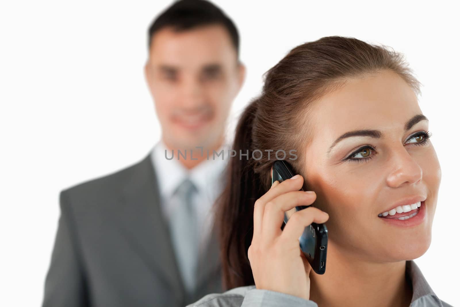 Close up of young businesswoman on the phone with colleague behind her against a white background