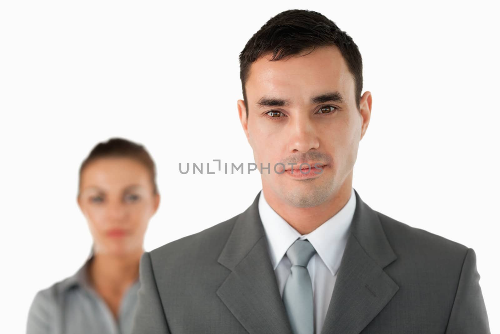 Close up of serious looking businessman with colleague behind him against a white background