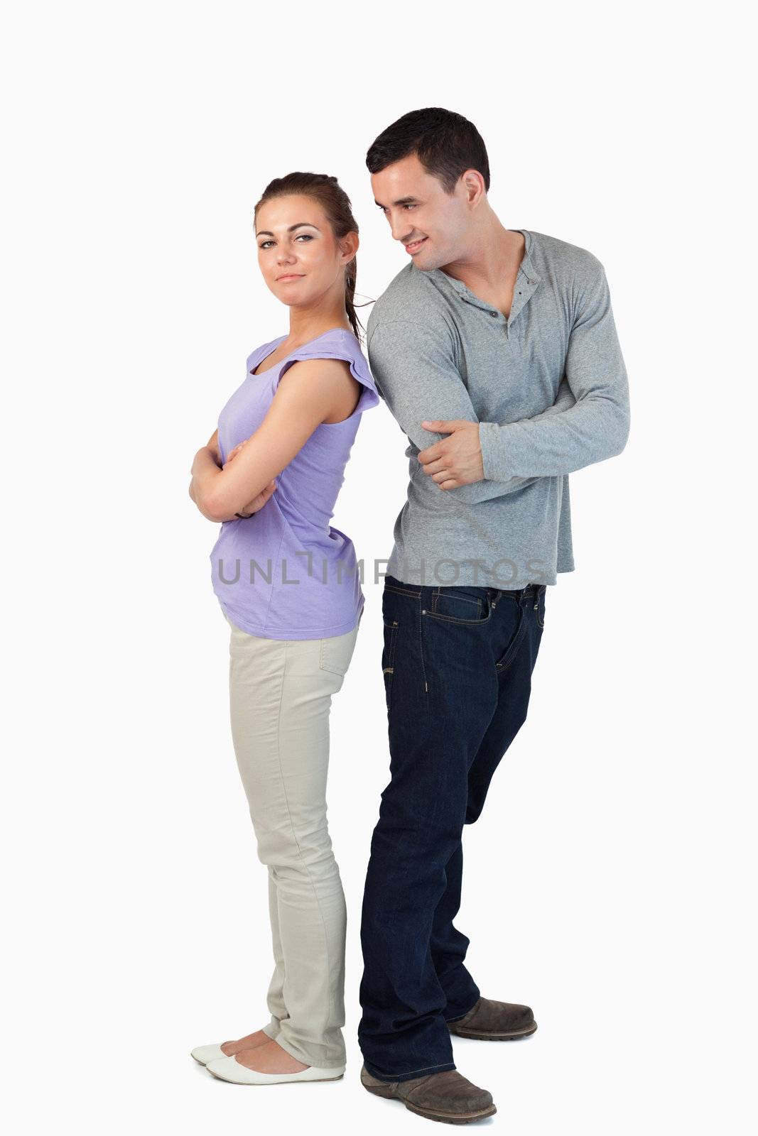 Young couple standing back-to-back to each other against a white backgrounf