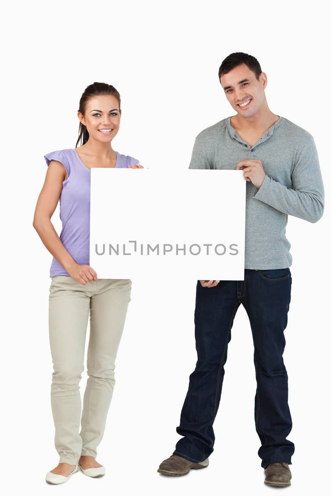 Young couple holding sign against a white background