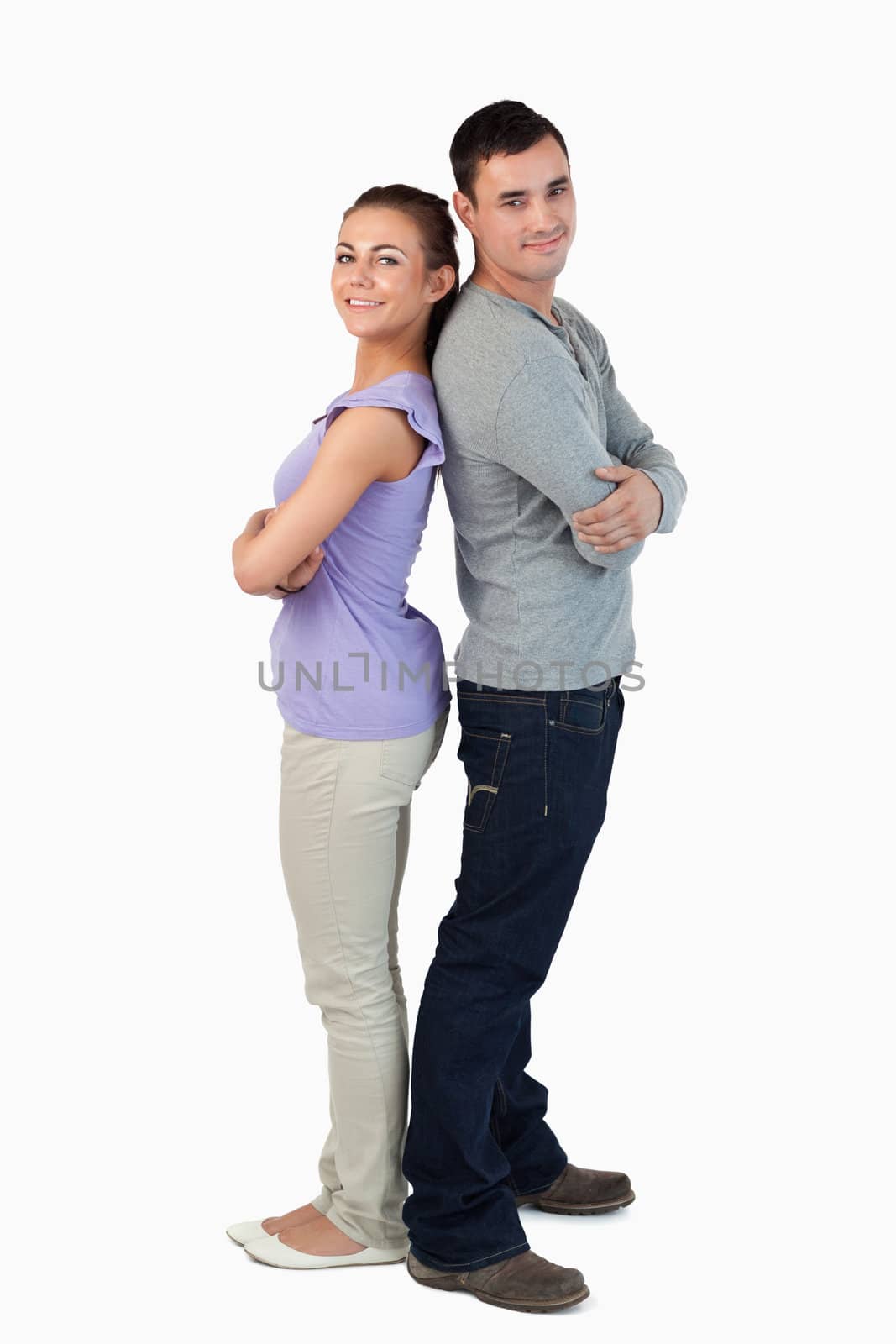 Happy young couple standing back-to-back against a white background