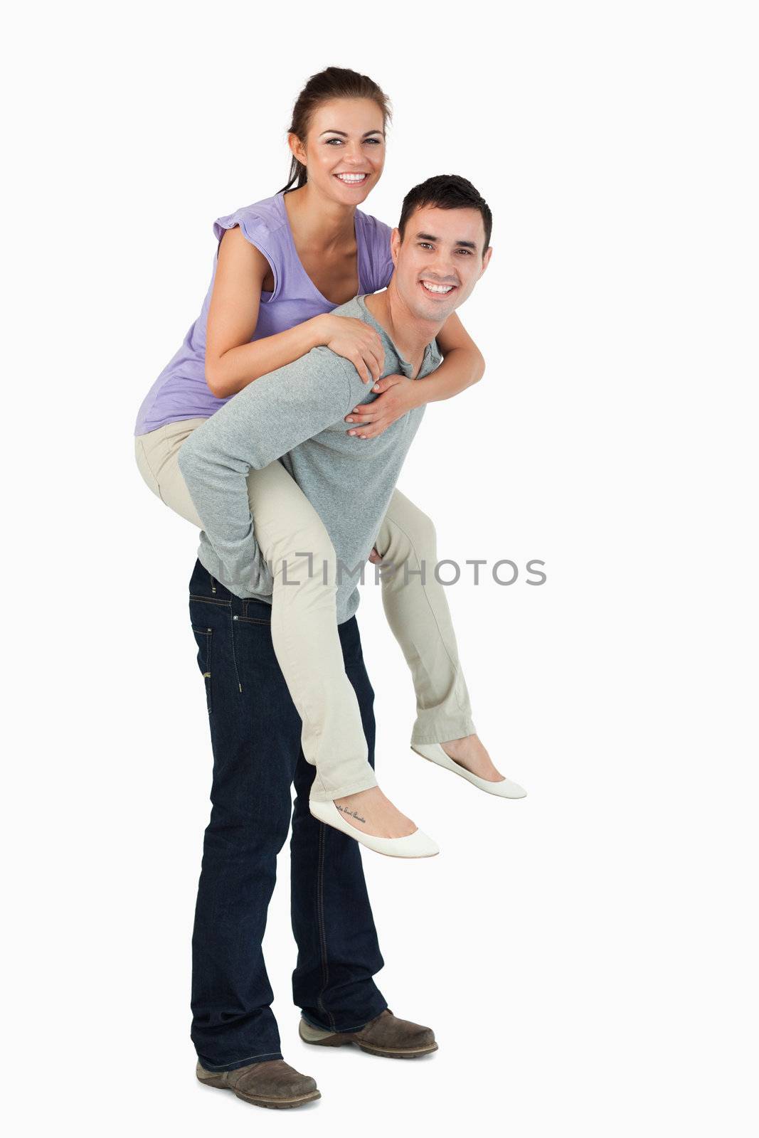 Young male carrying his girlfriend piggyback against a white background