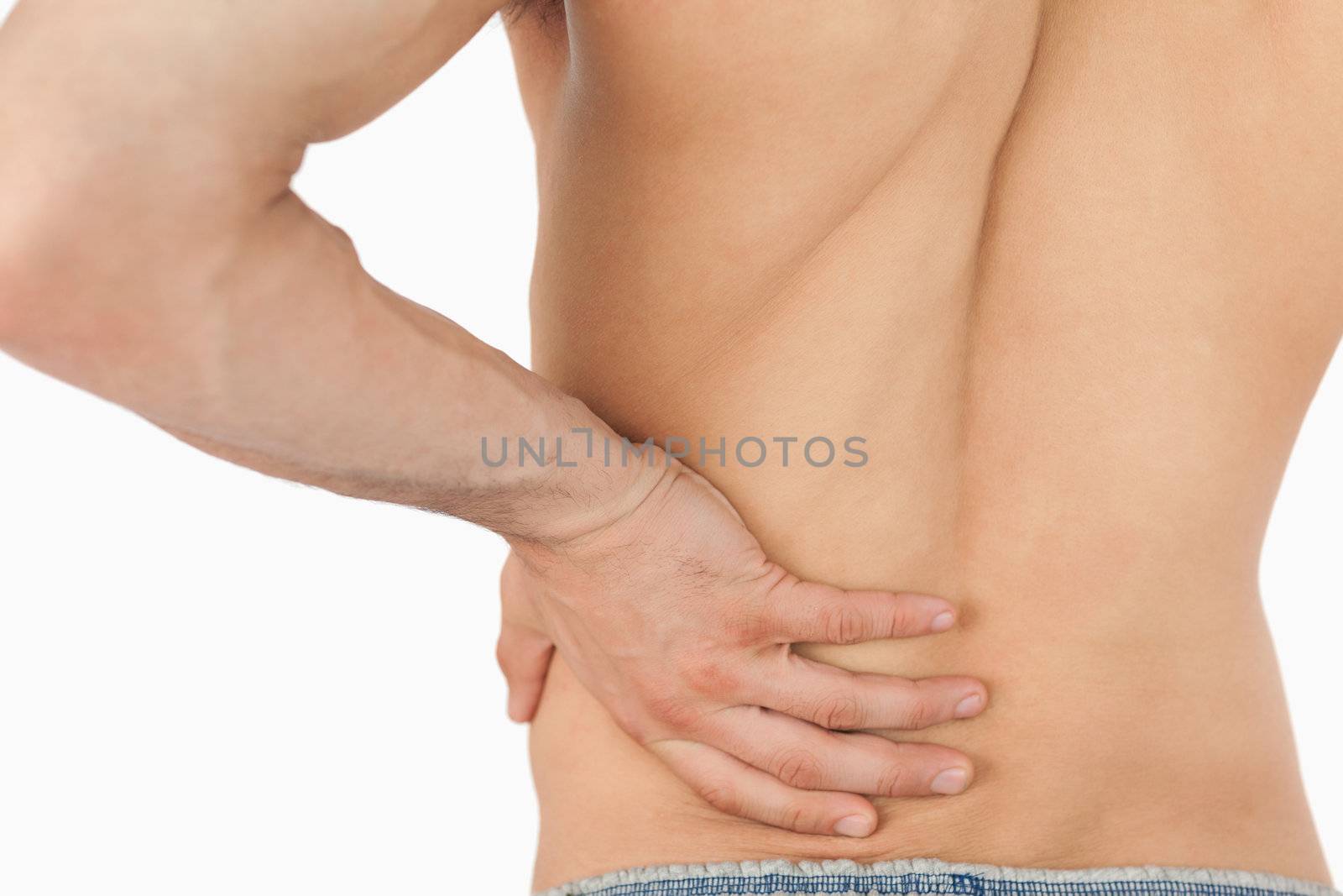 Young man experiencing back pain against a white background