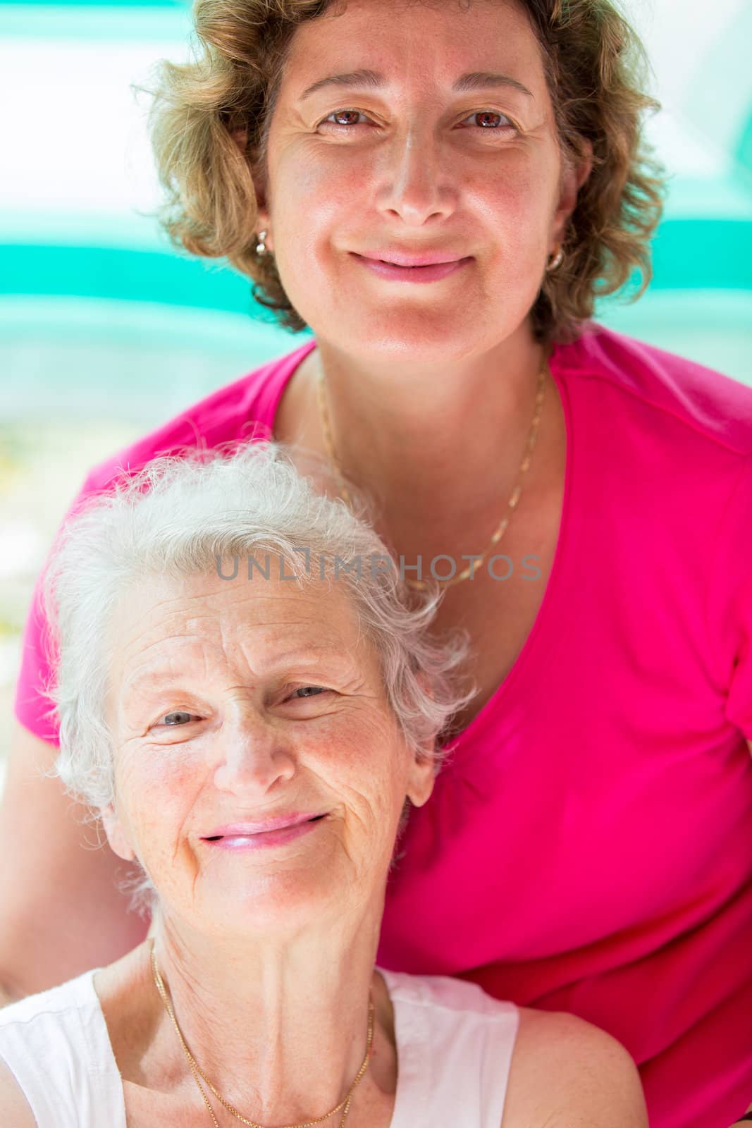 Old mother and her daughter posing with satisfied look.