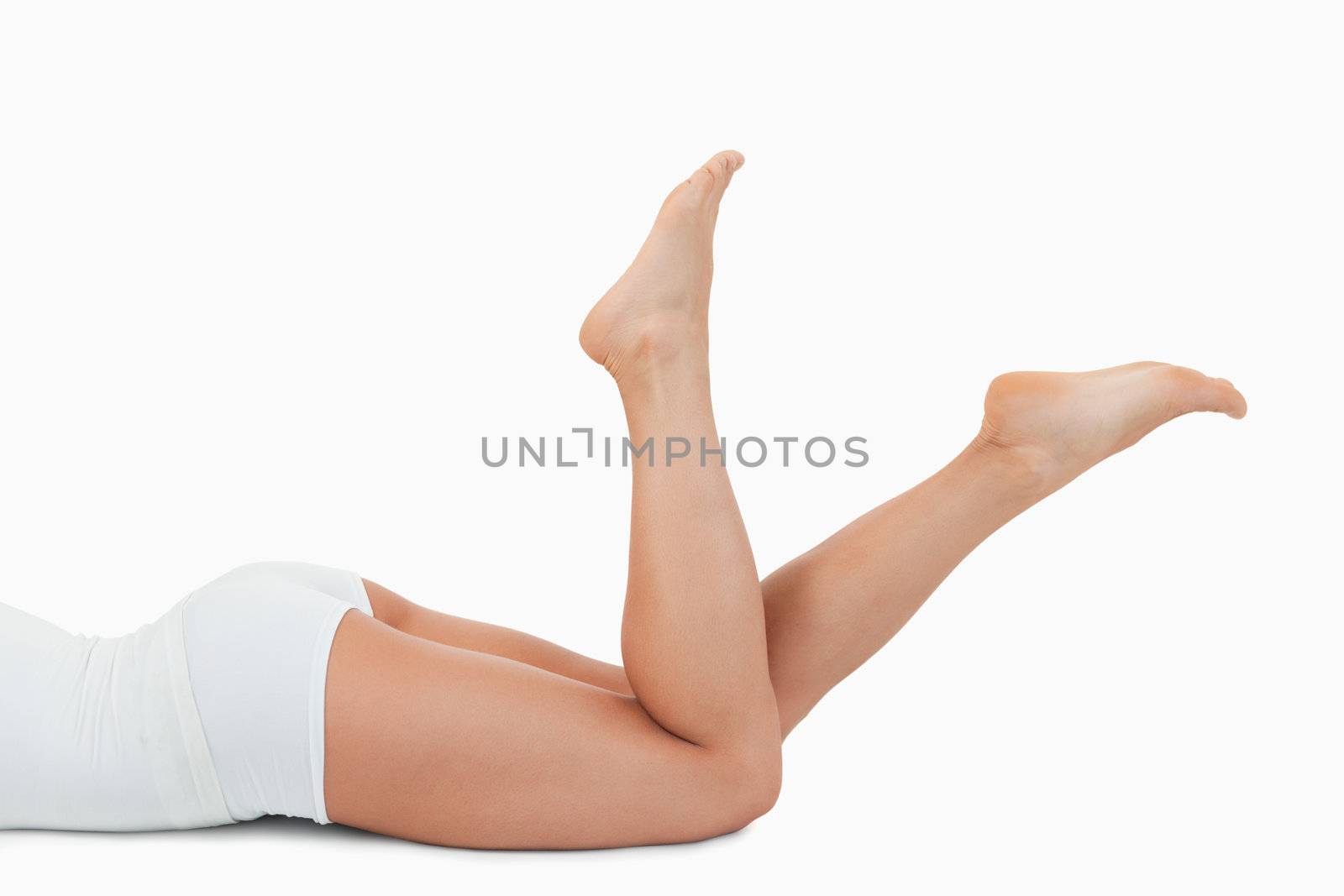 Feminine body lying on her belly against a white background