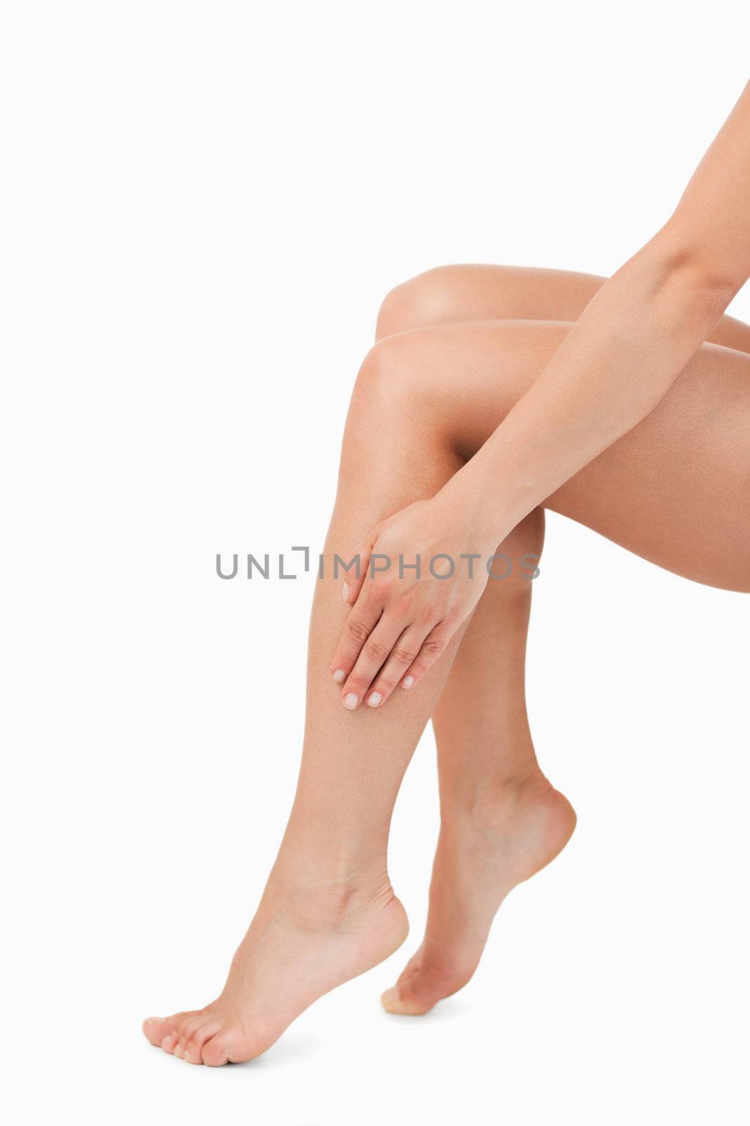 Portrait of a feminine hand touching legs against a white background