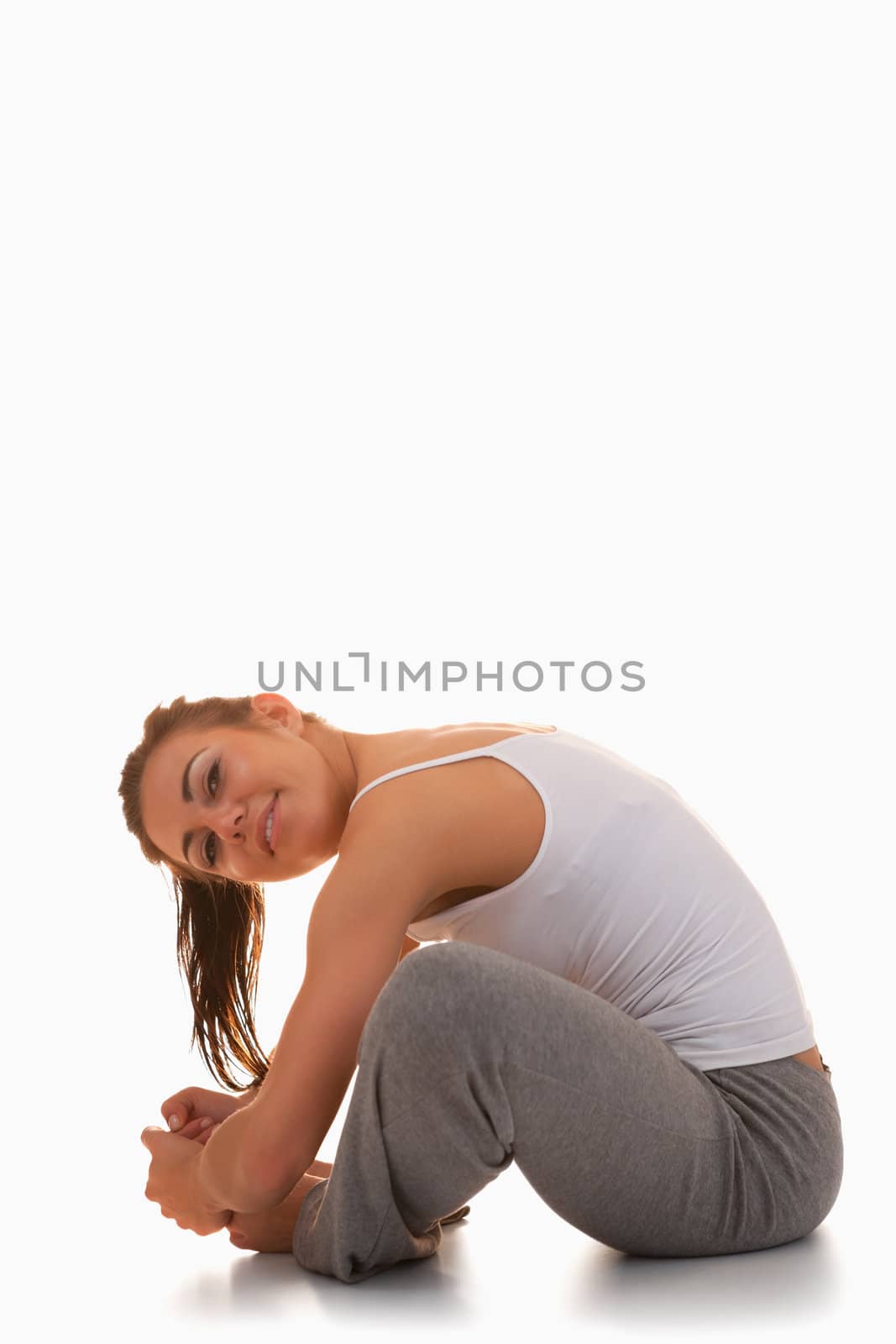 Portrait of a young woman stretching her legs against a white background