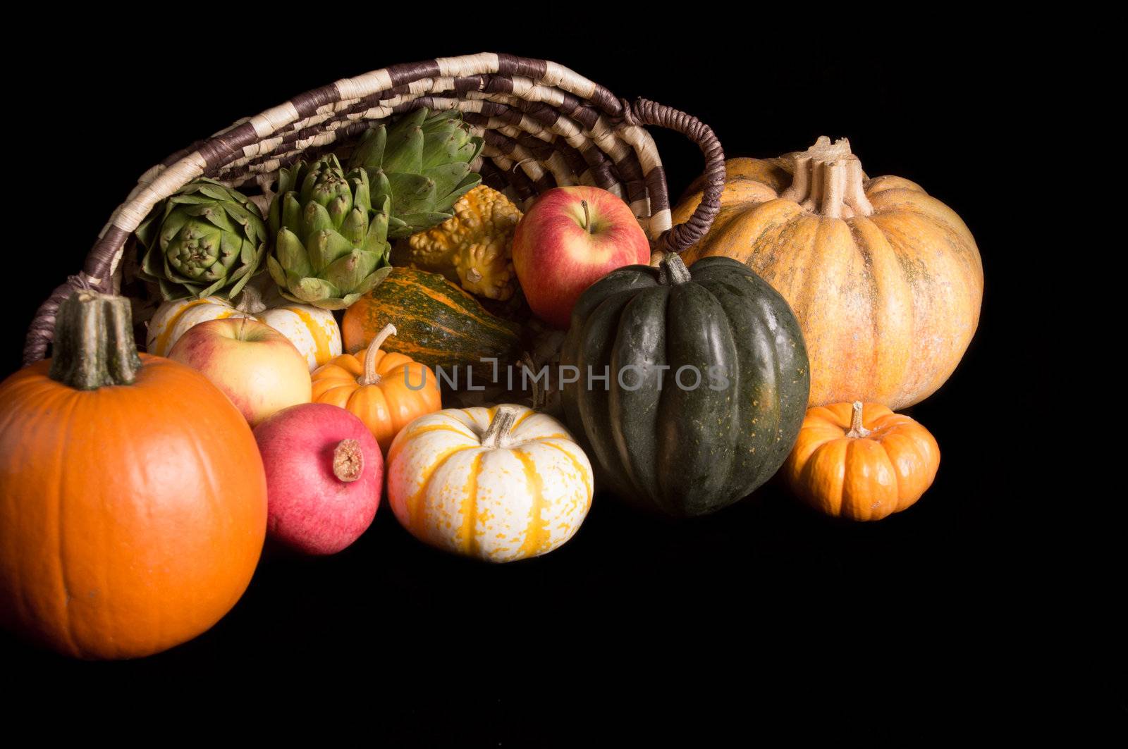 Cornucopia of fresh pumpkins, squash, apples and pomegranet isolated on black background