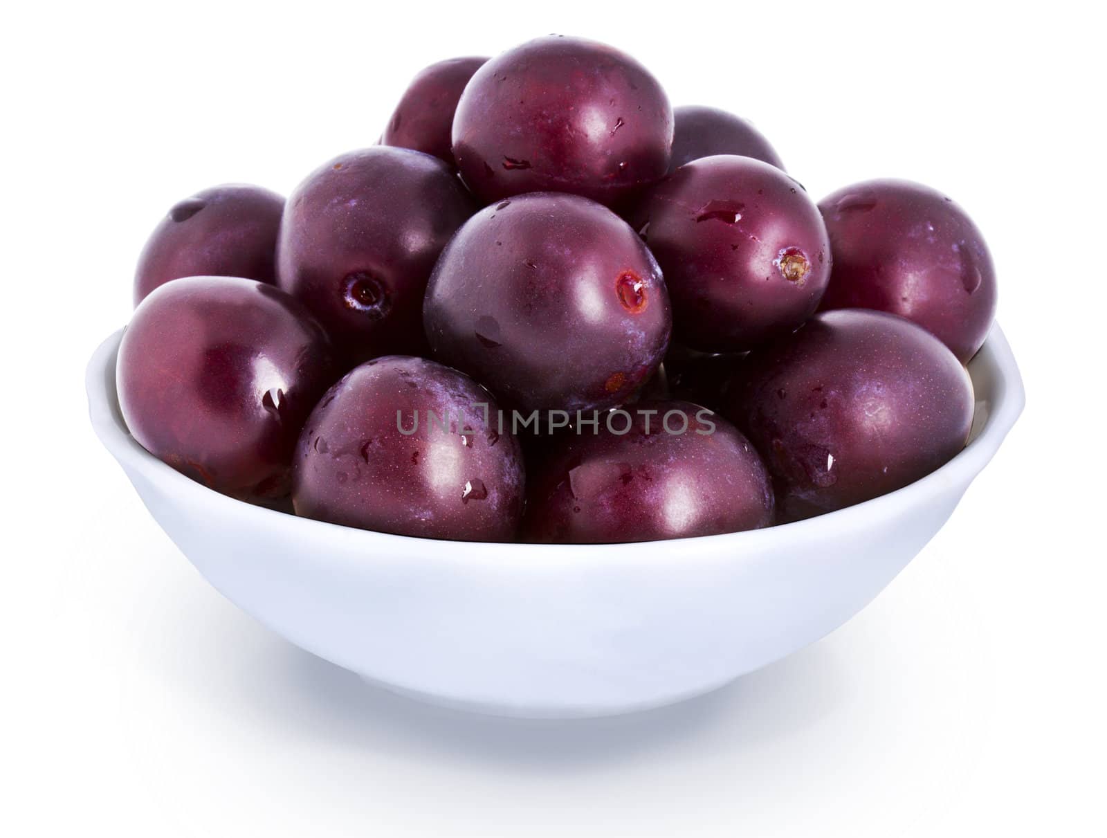 Fresh plums in plate with water drops isolated on white background