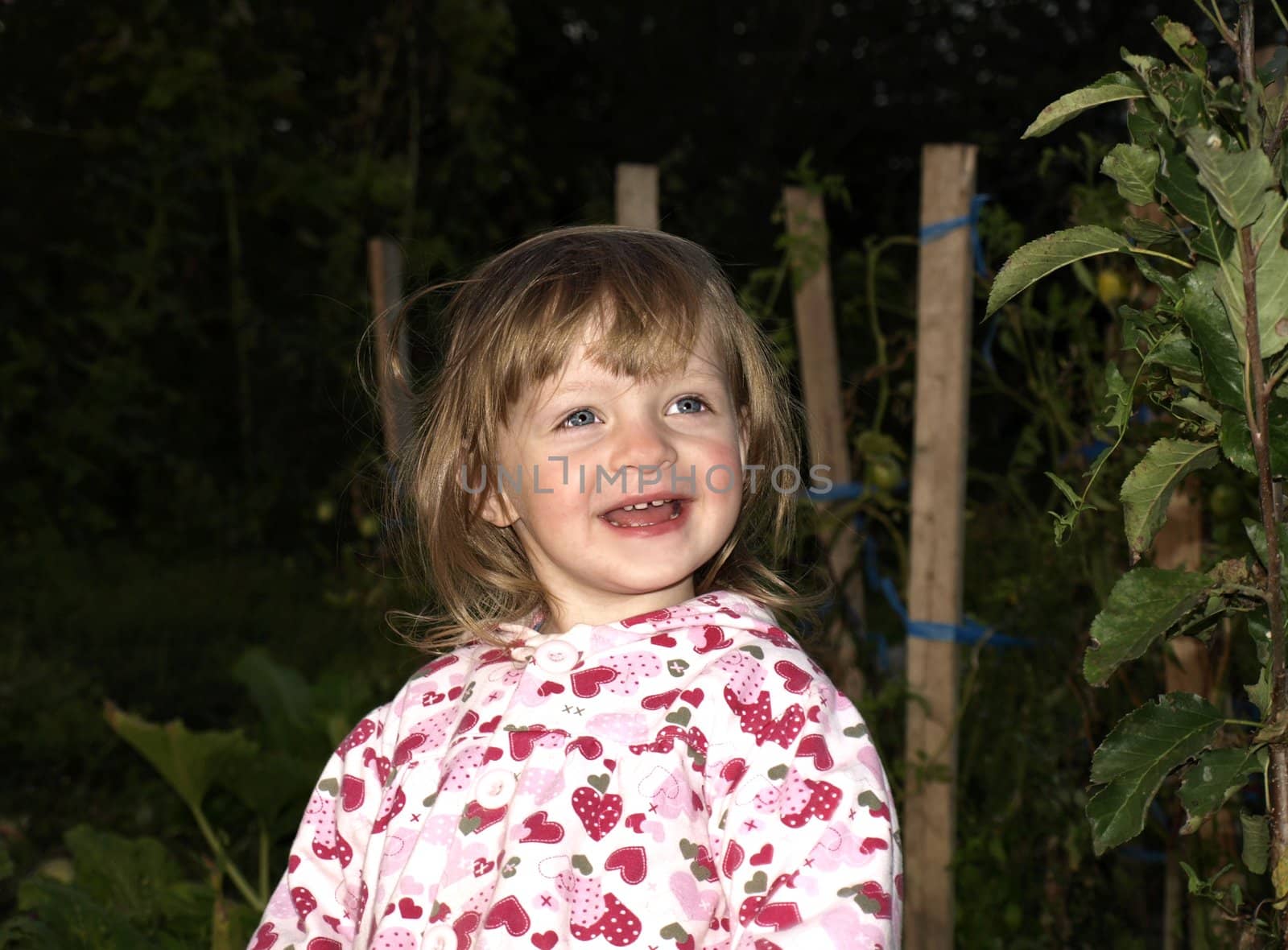 Cute smiling little girl on evening garden background