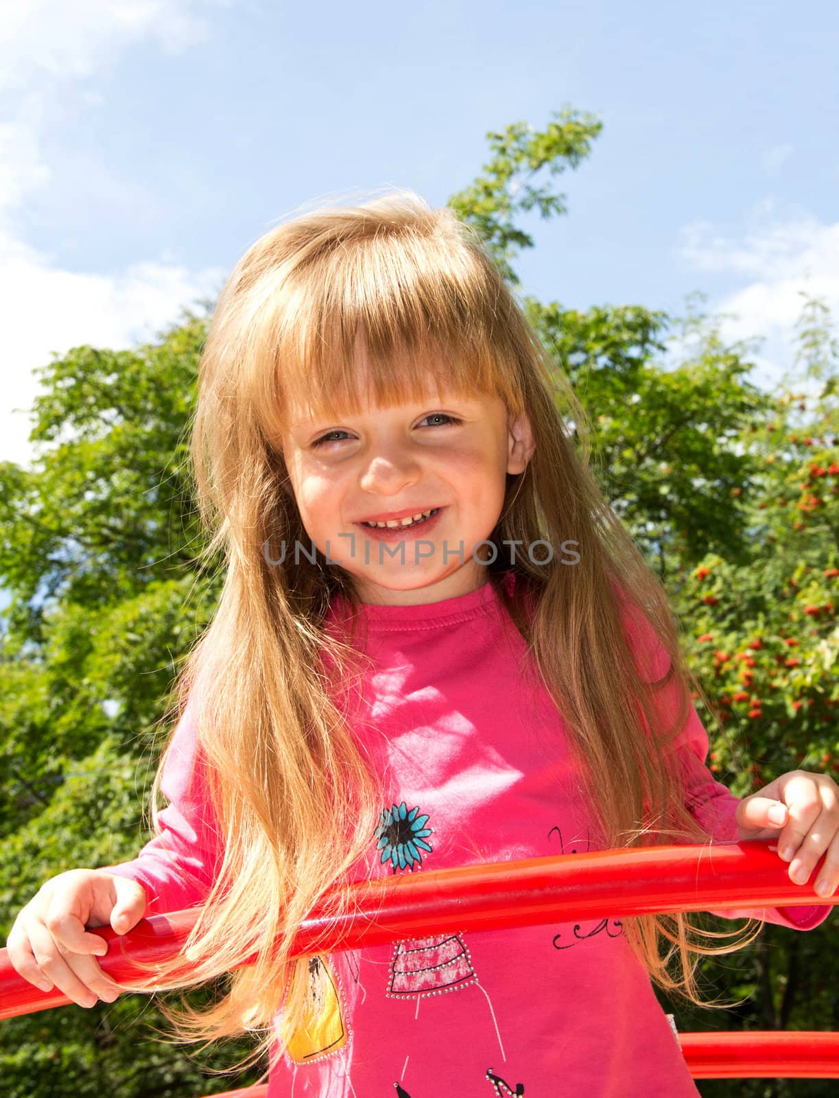 Cute smiling little girl with long hair playing in the park