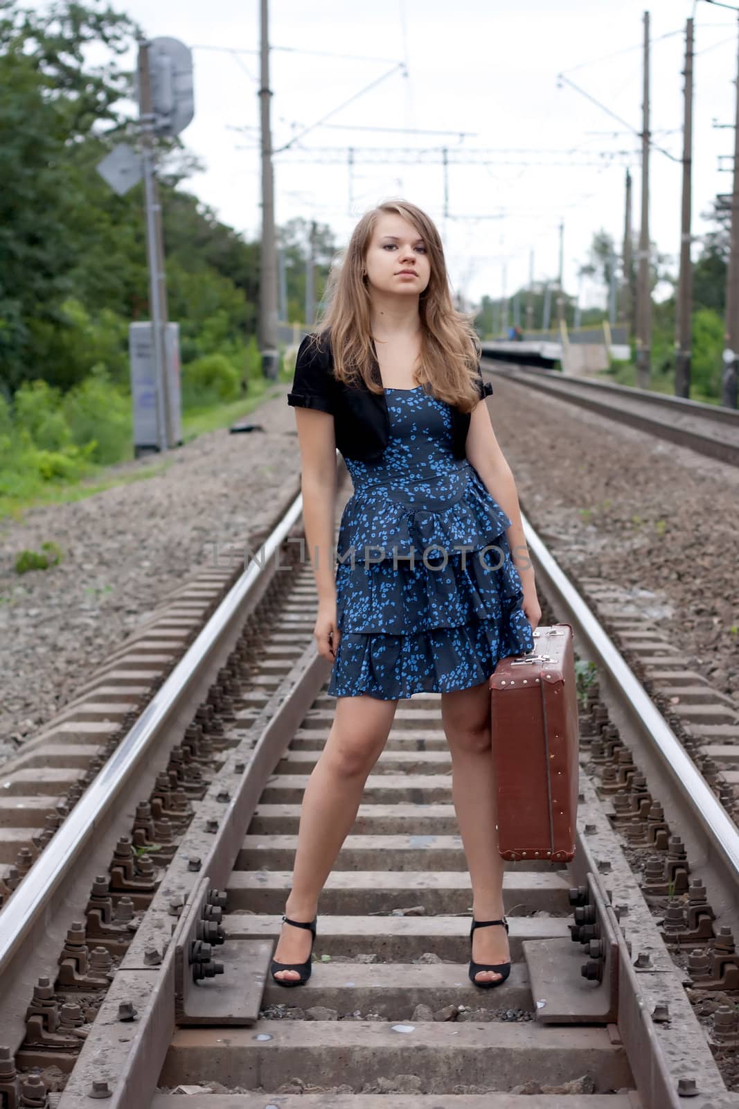 Girl with a suitcase standing on the rails shooting outdoors