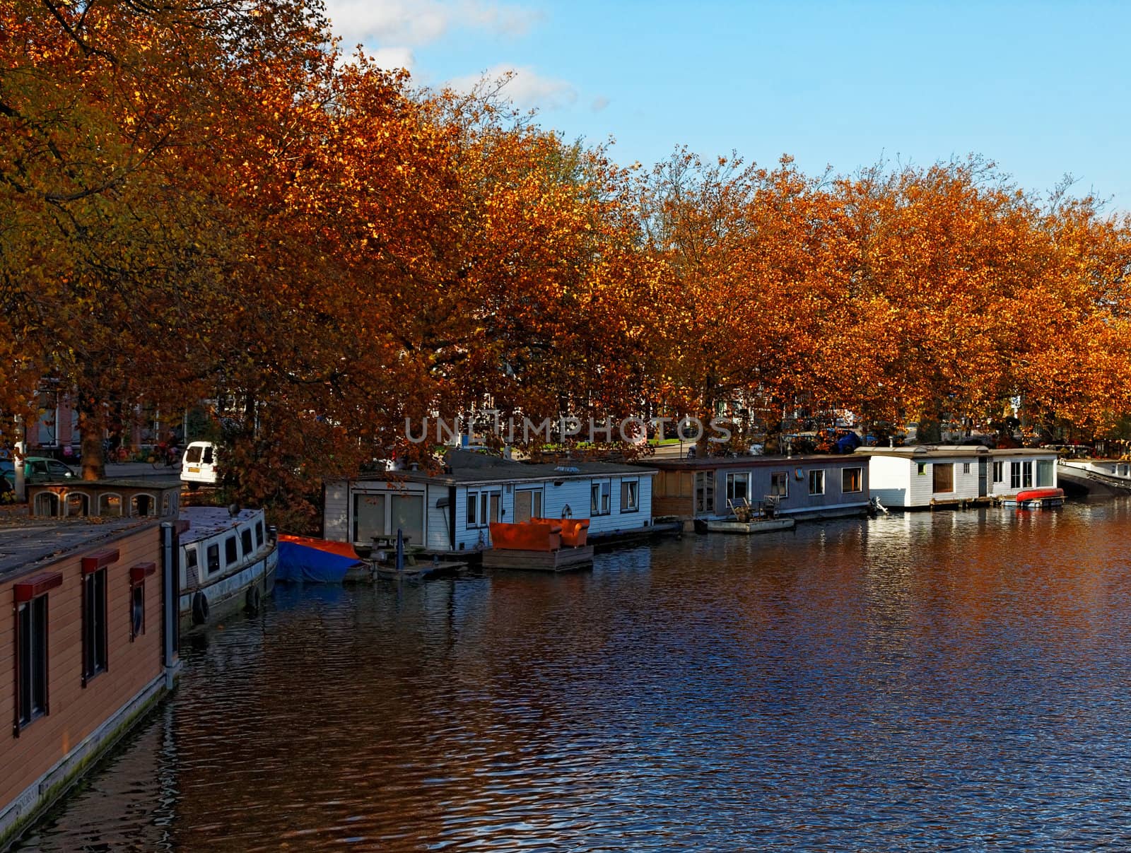 Autumn image of a typical canal with floating houses in Amsterdam.