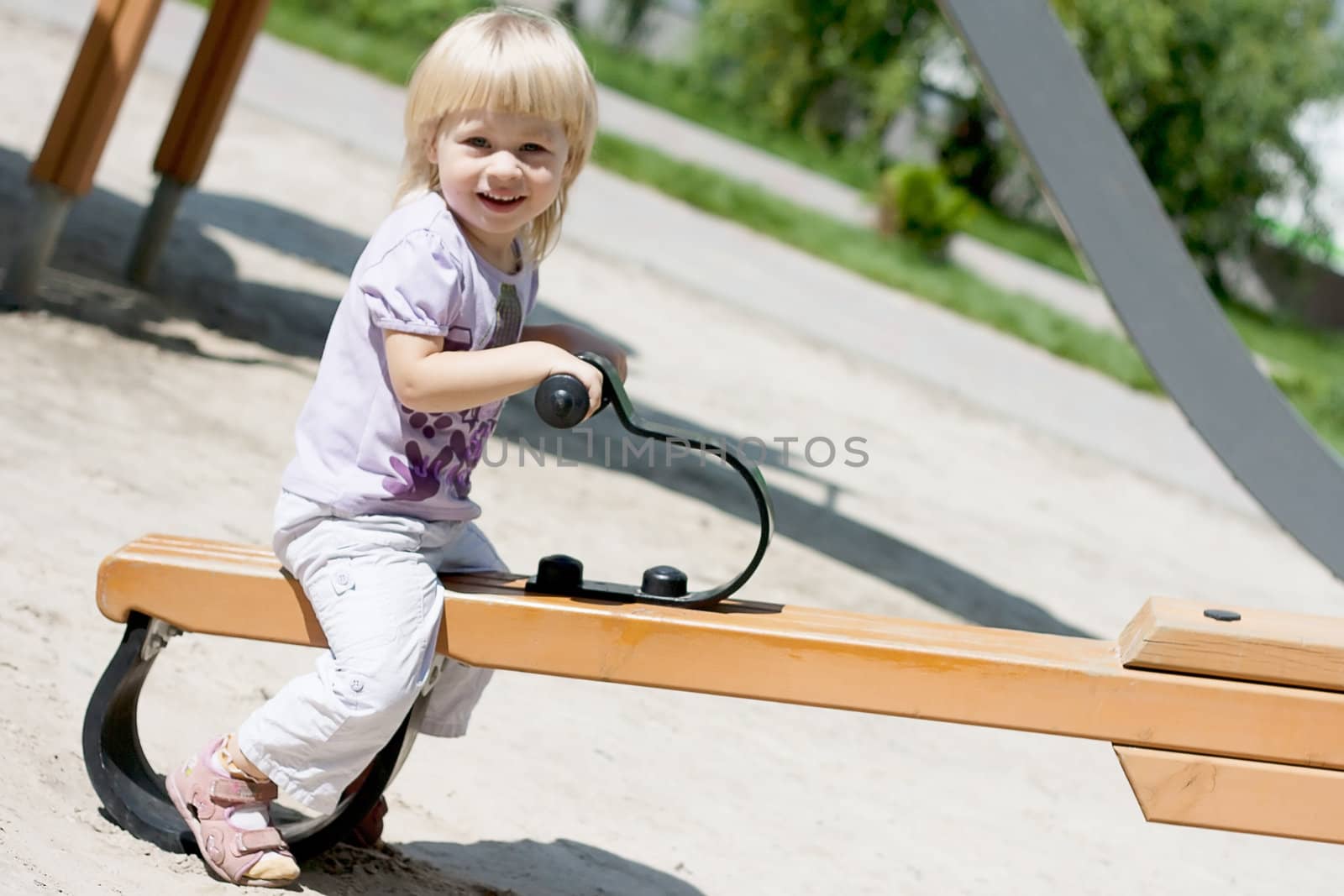 Happy little girl riding on a swing in the park shooting