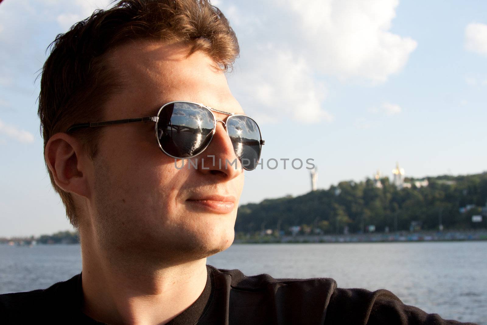 The guy in sunglasses against the background of sky and water