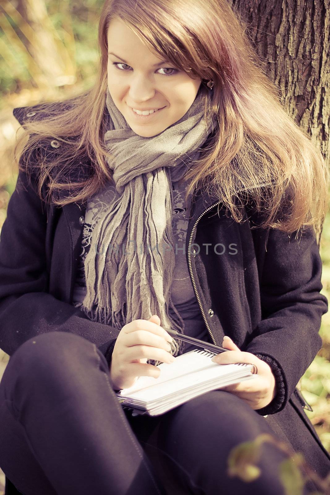 A girl writes on a pad in the park outdoors shooting