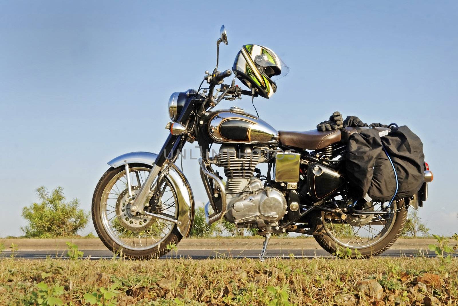 Old style motorcycle parked in a generic highway road rural scene. Location of shot is Maharashtra India