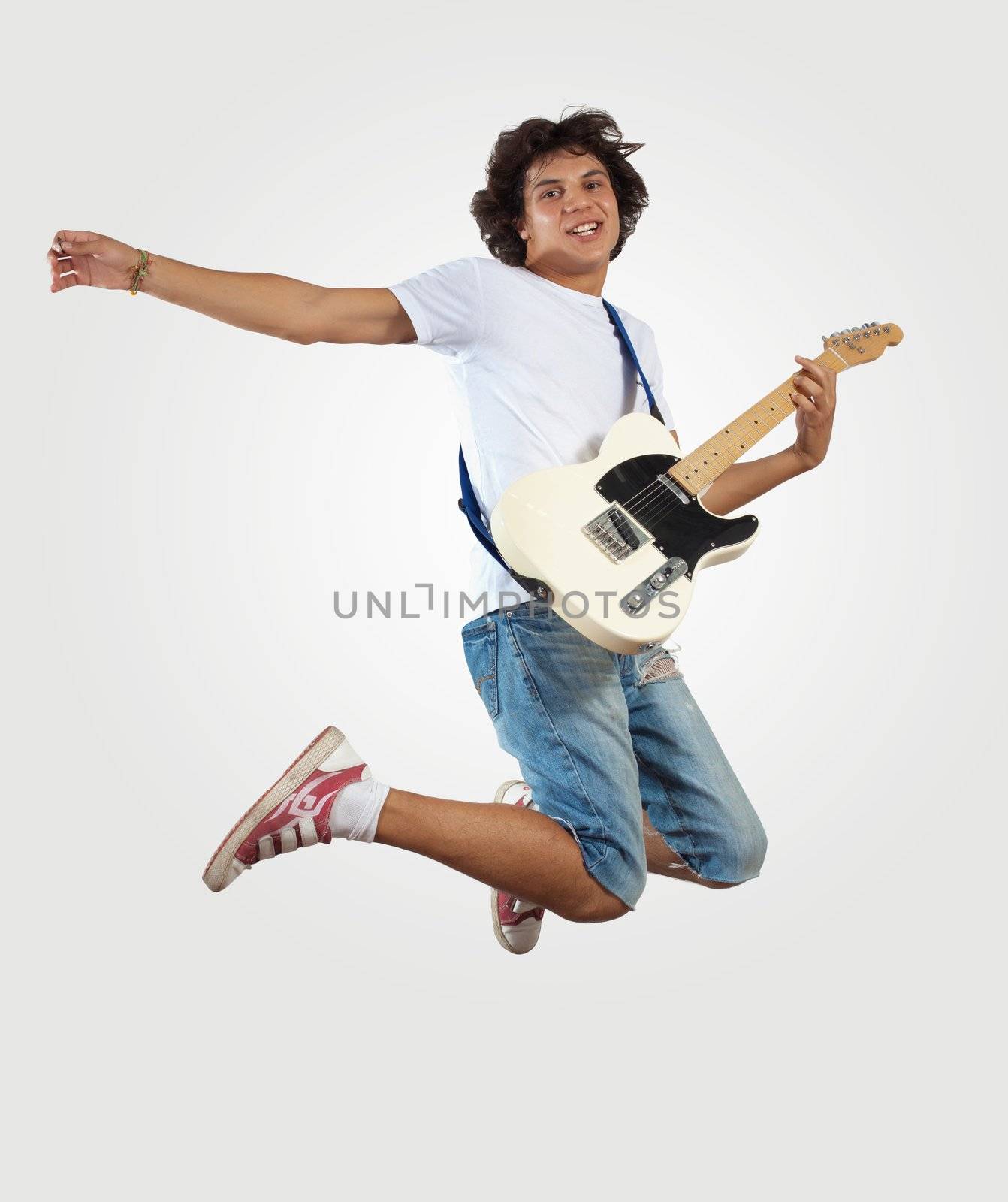 young man playing on electro guitar and jumping