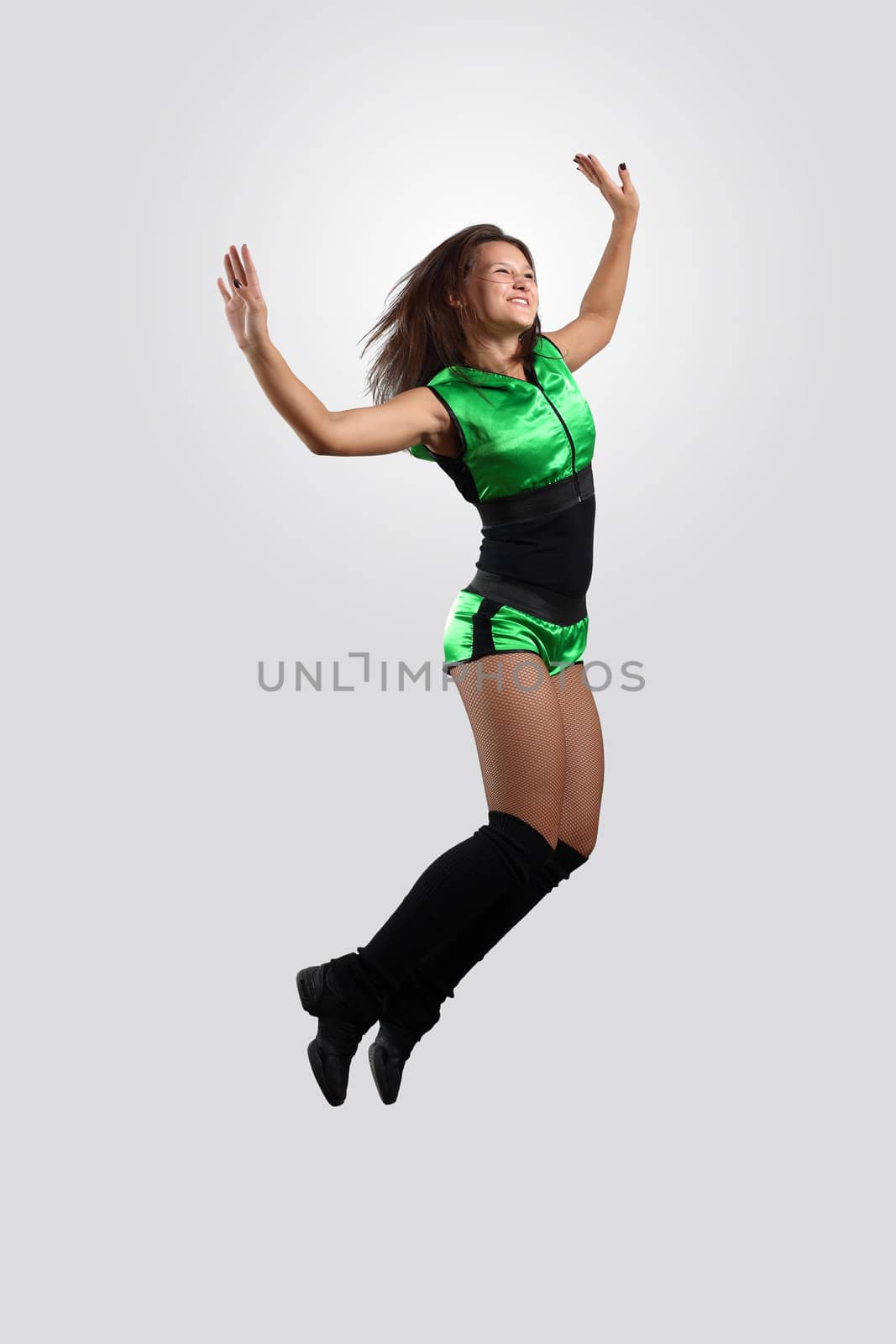 Young female dancer jumping against white background