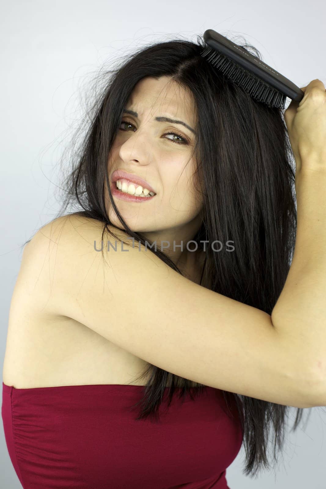Beautiful woman trying to brush her messy hair by fmarsicano