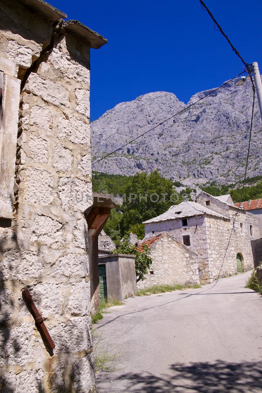 Typical stone houses in old village of Tucepi below towering mountains of Biakovo nature park on Makarska Riviera in Dalmatia, Croatia