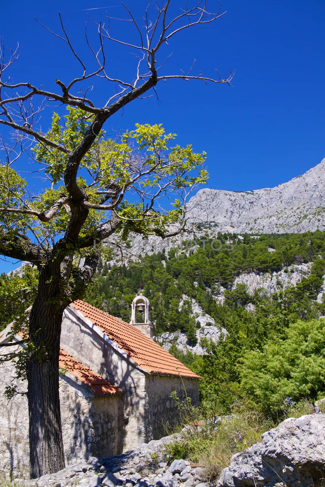 Old stone chapel near village of Tucepi below towering mountains of Biakovo nature park on Makarska Riviera in Dalmatia, Croatia