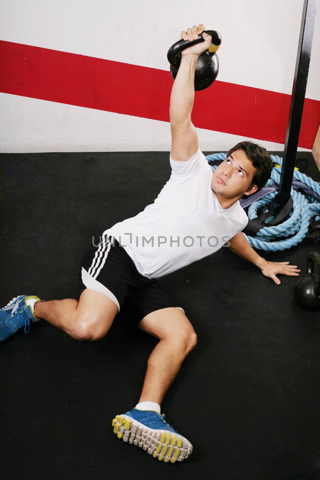 Young man doing kettlebell workout on gym