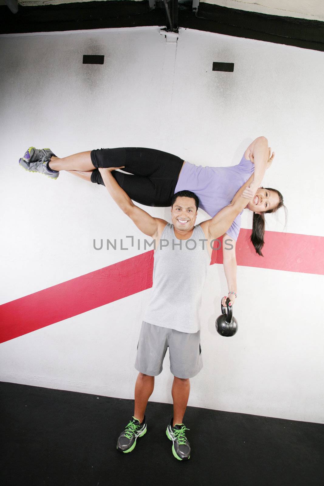 Handsome man lifting a beautiful woman at the gym by dacasdo