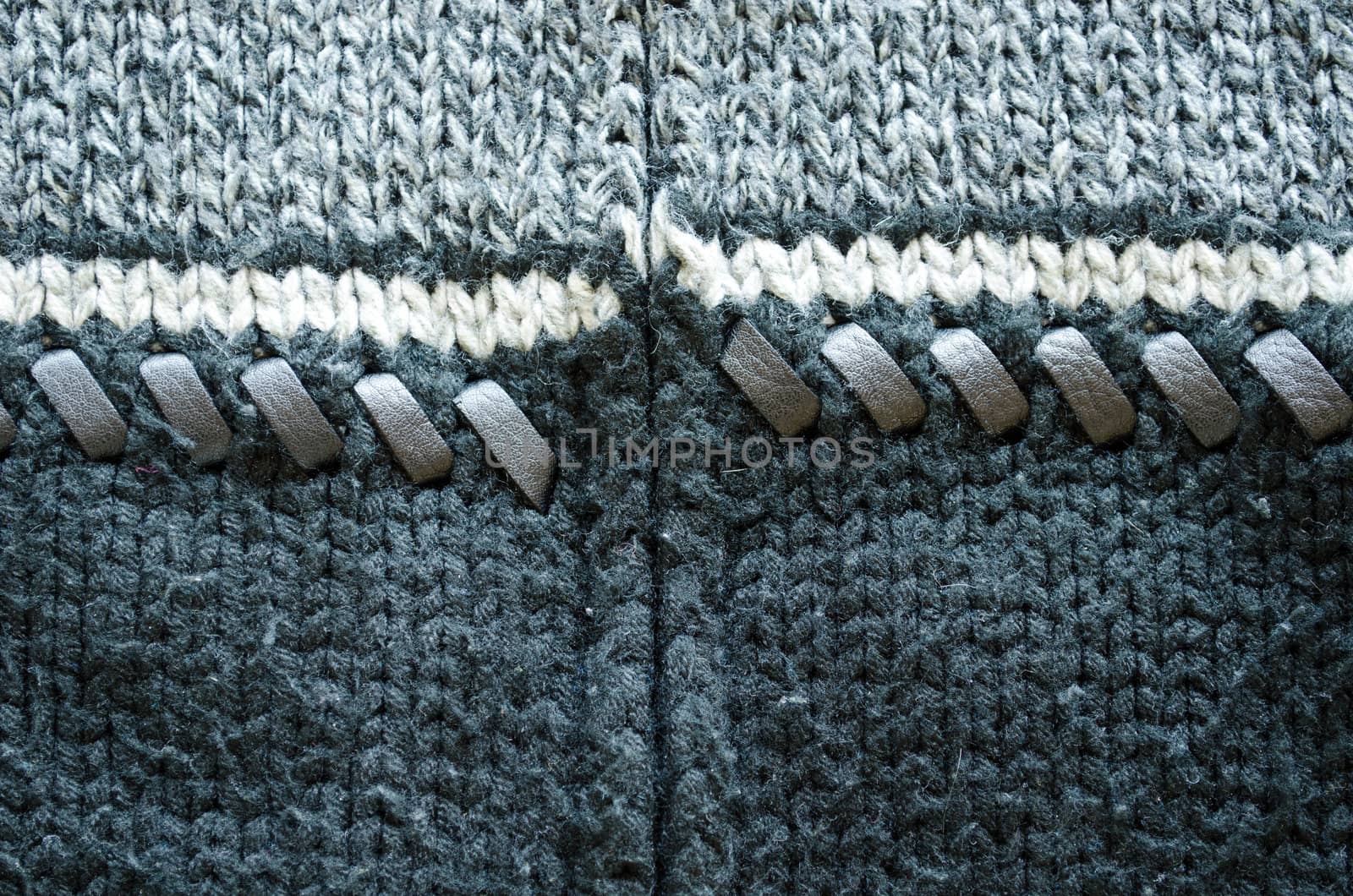 Closeup of wool knit sweater texture decorated with leather stitch. White grey and black colors background