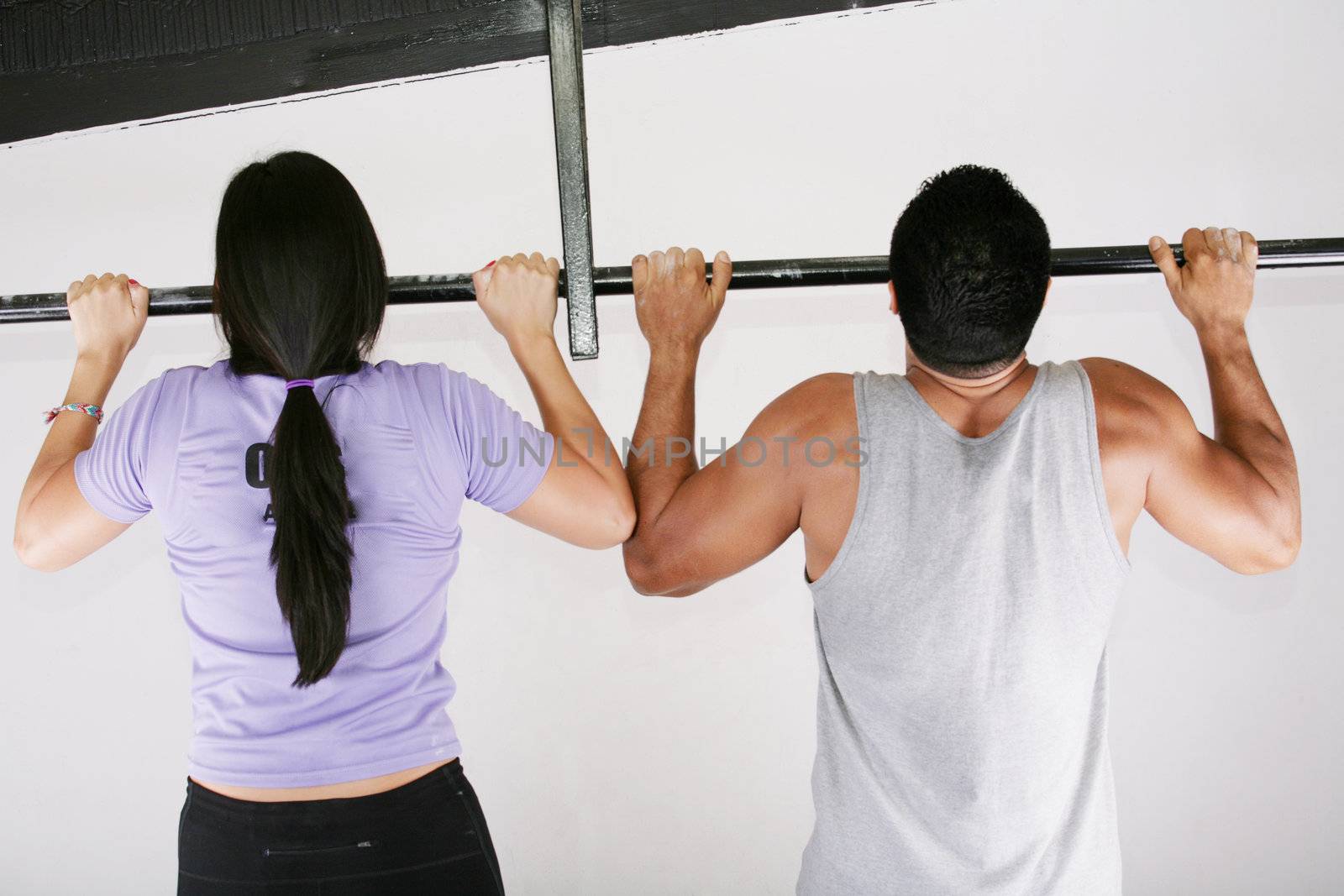 Young adult fitness woman and man preparing to do pull ups in pu by dacasdo