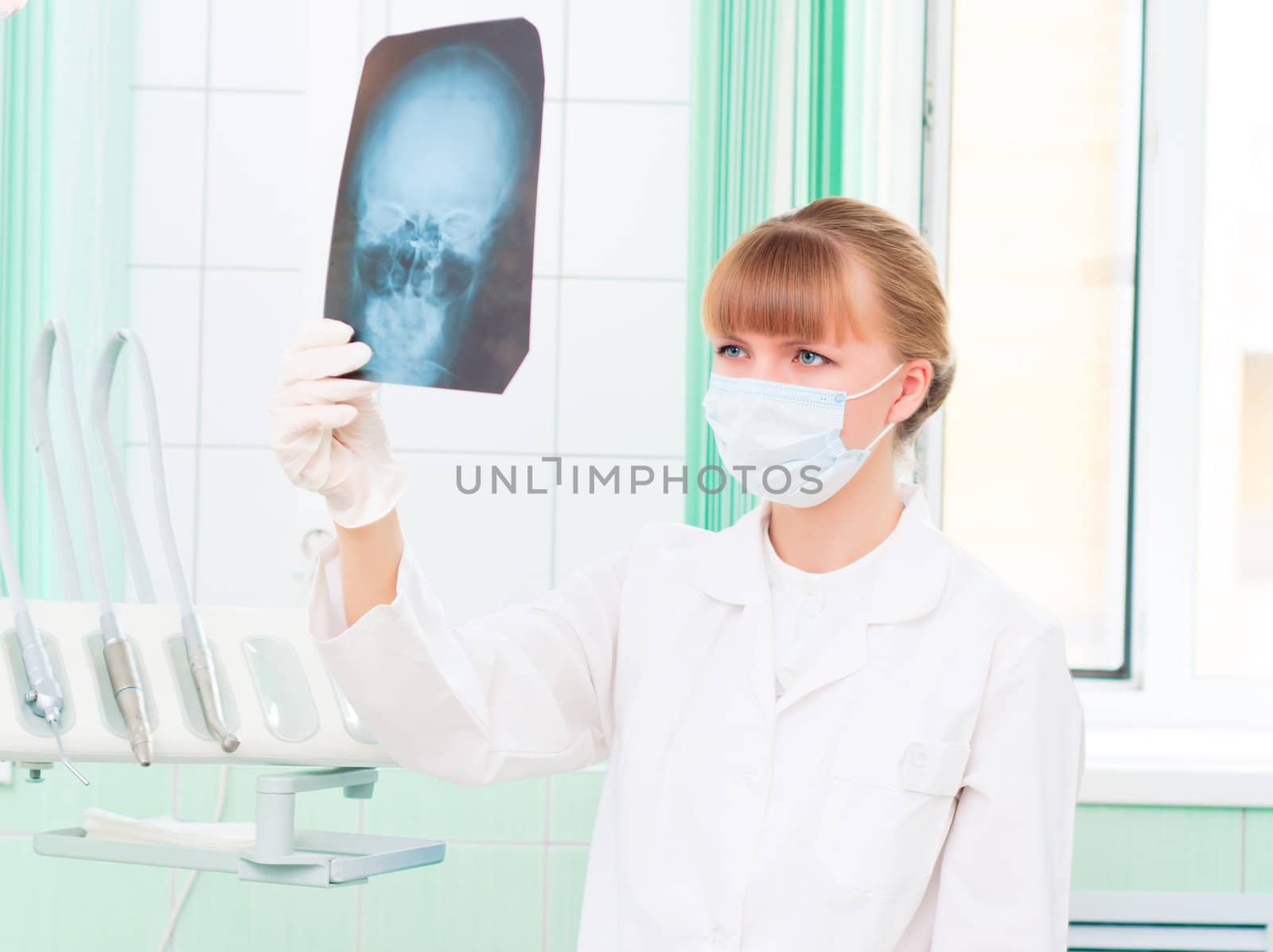 Young woman in protective mask dotstor looks at an X-ray of skull