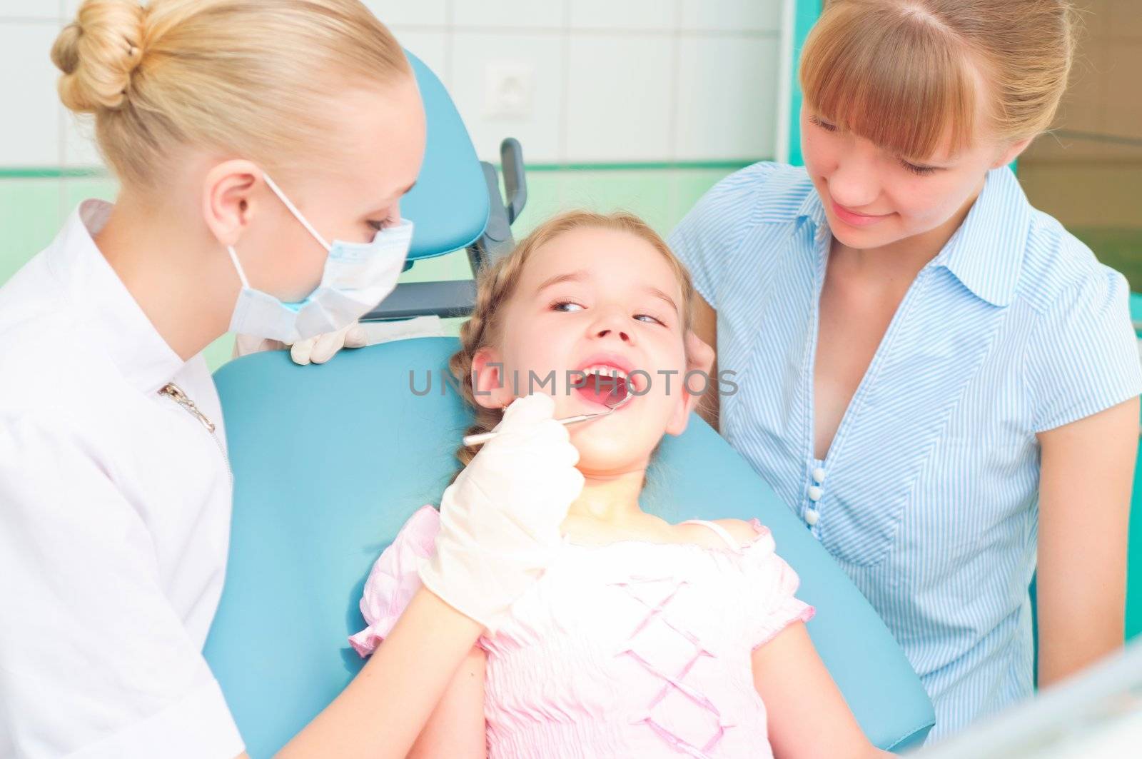 female dentists examines a child, my mother was sitting beside him and soothes baby