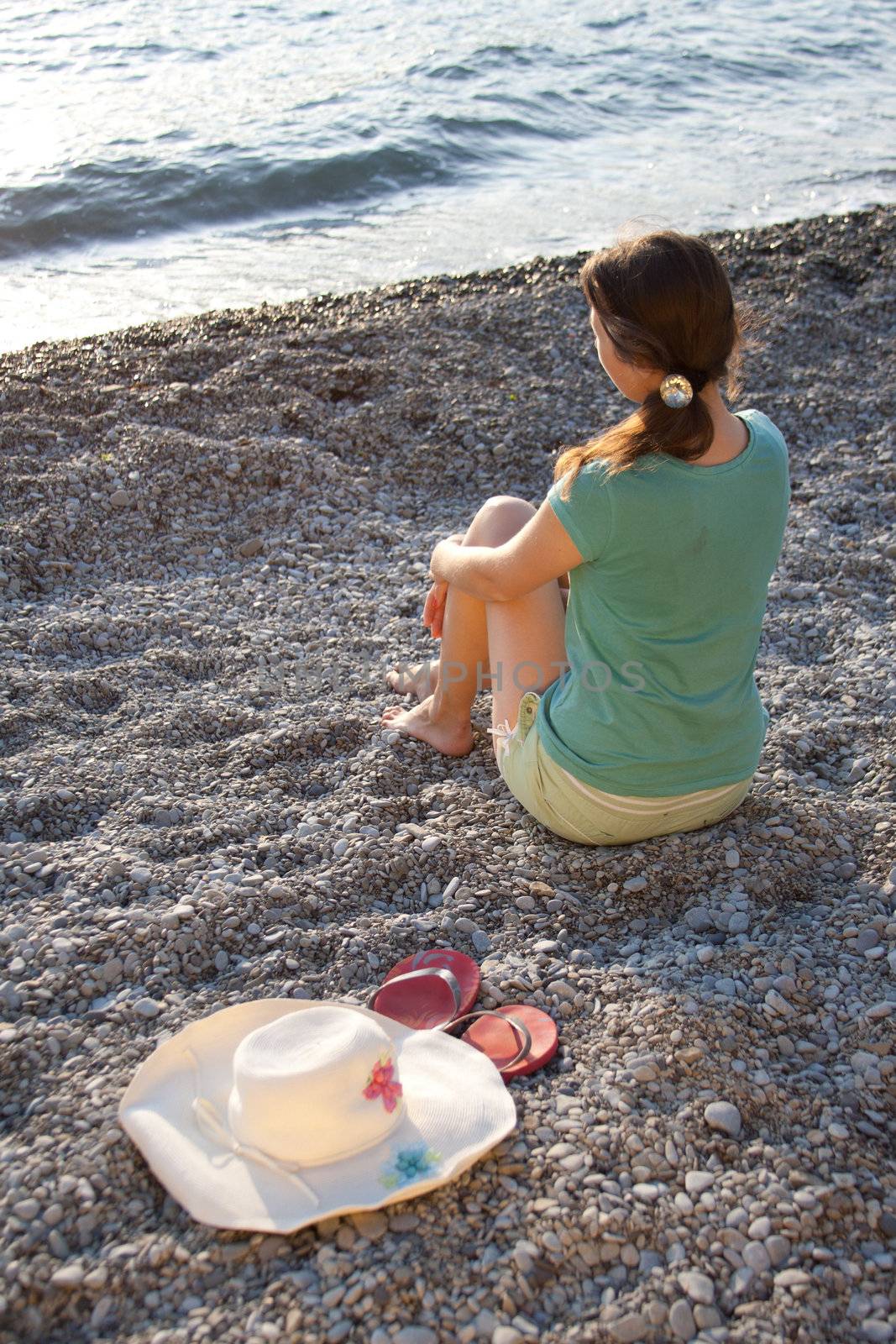 The girl, hat and flip-flops on the stones outdoors shooting