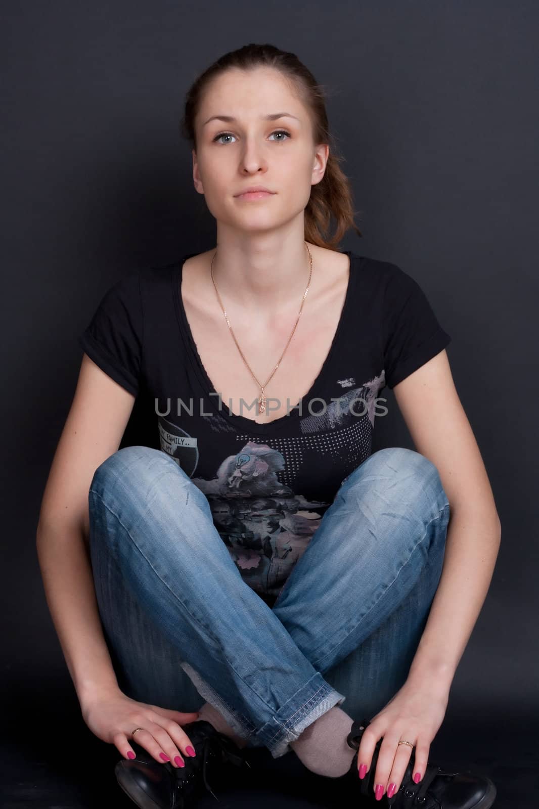 The girl in blue jeans sitting on the floor of studio shooting