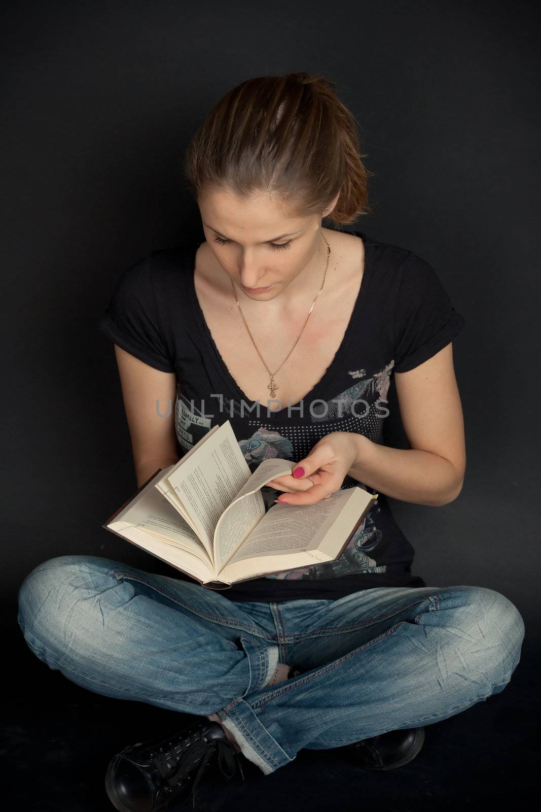A girl sits and leafs through a book