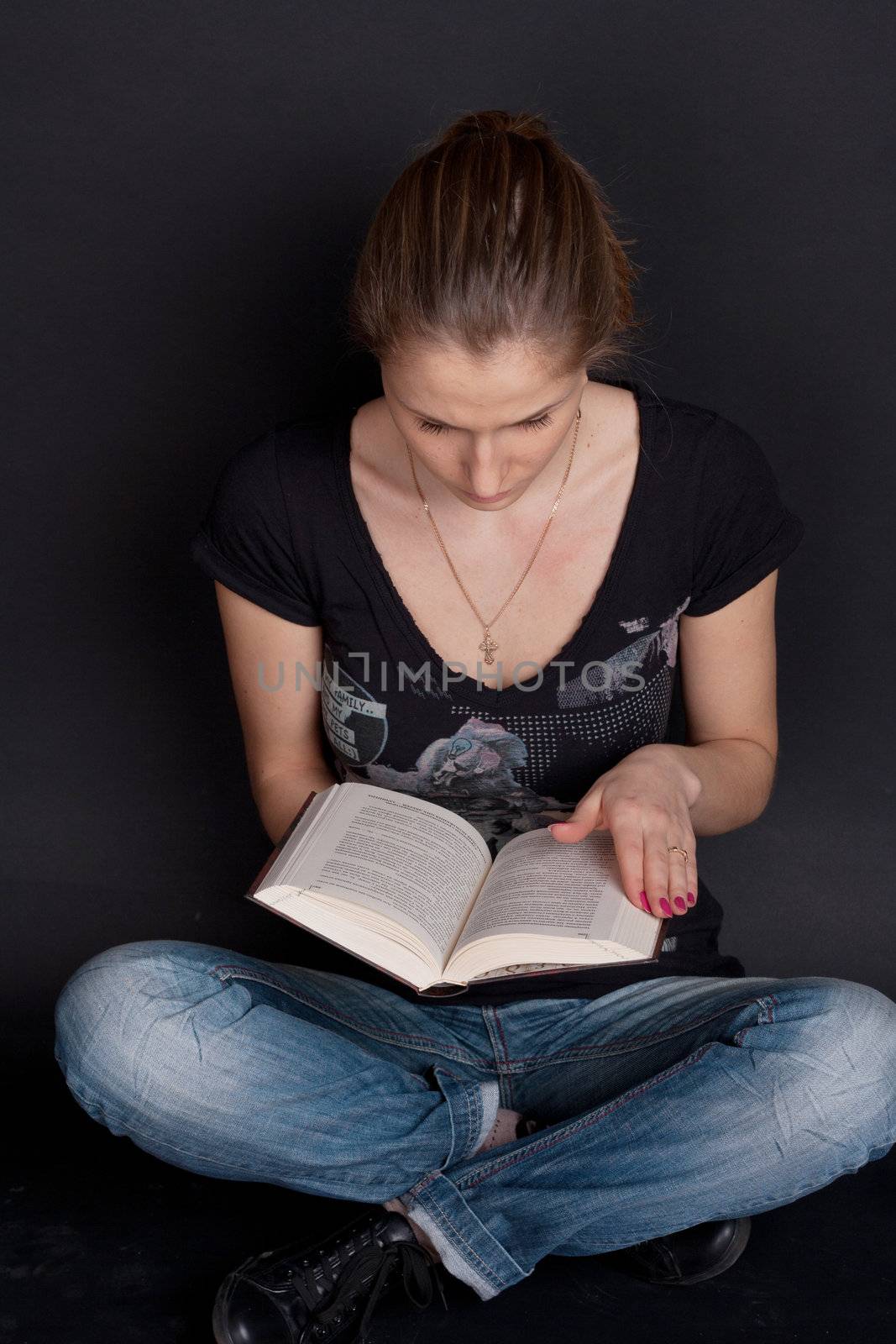 A girl sits and leafs through a book