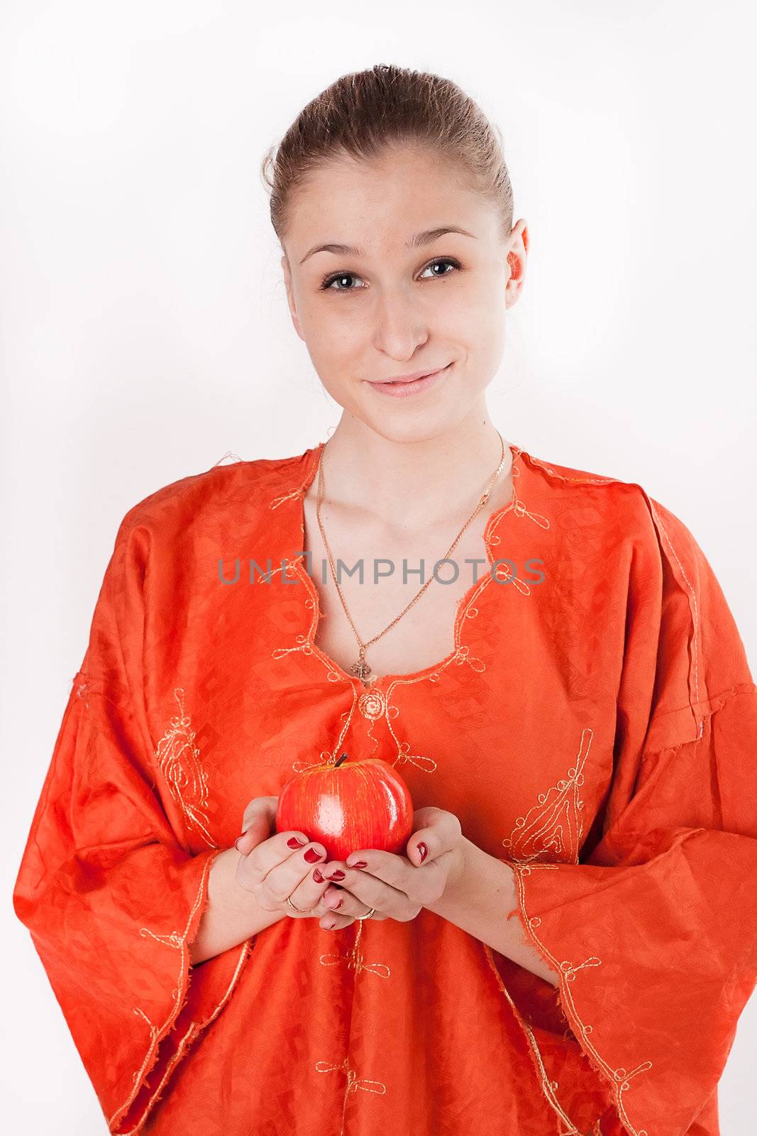 Girl in orange dress offers a red apple studio photography