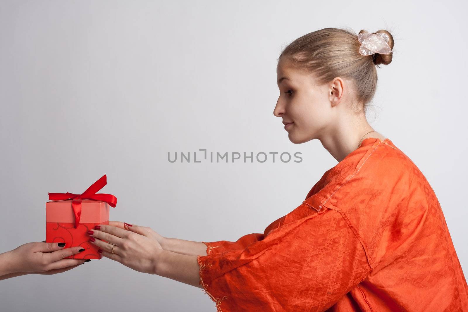 Girl in orange dress on a light background receives a gift