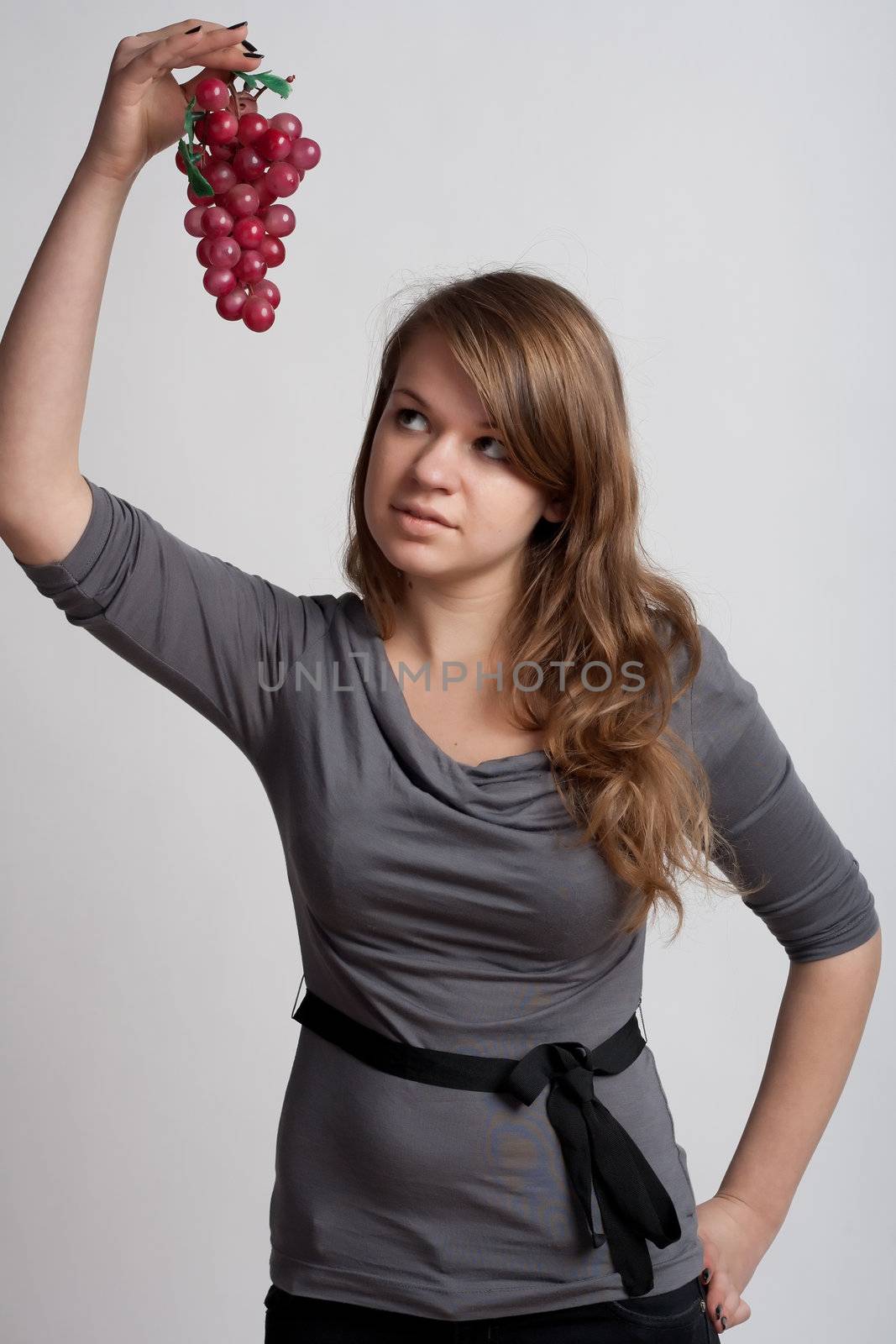 girl on a white background with grapes in his hand