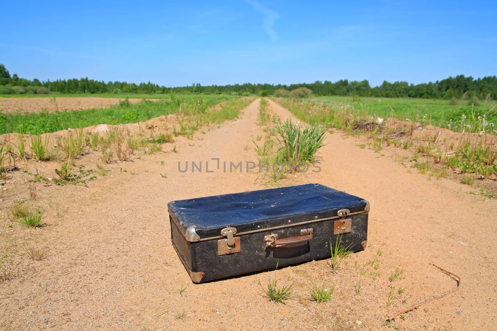 old valise on rural road by basel101658