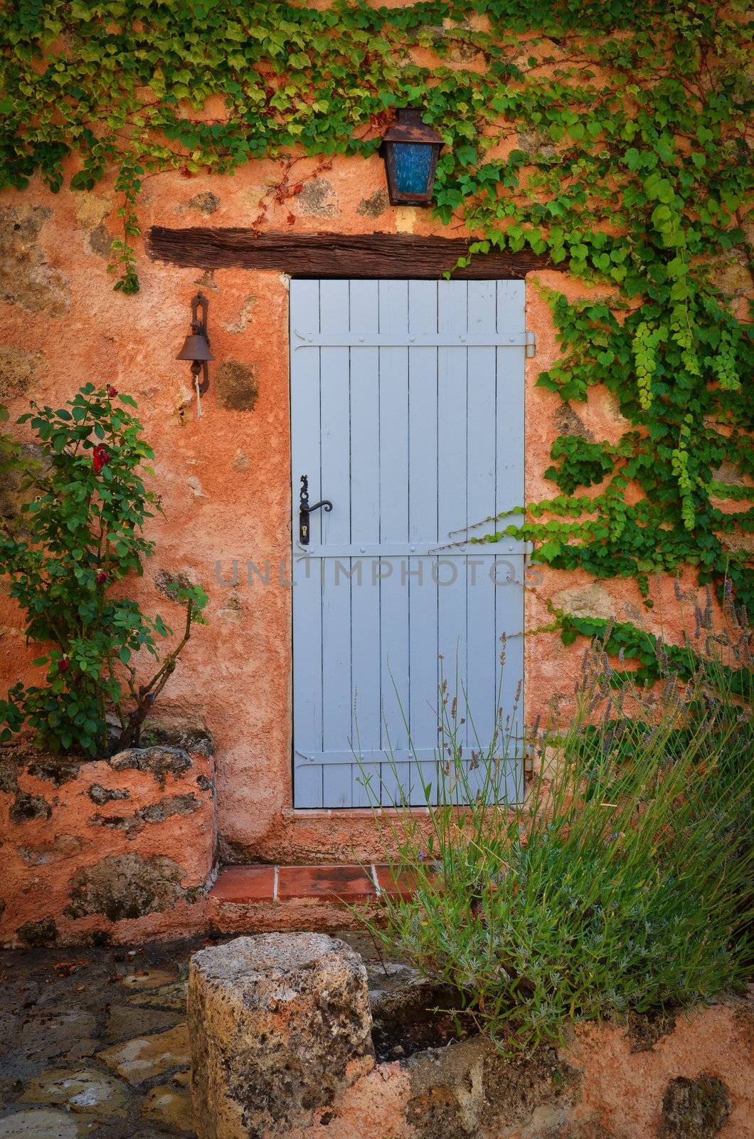 Old blue entrance door in orange wall, Provence, France