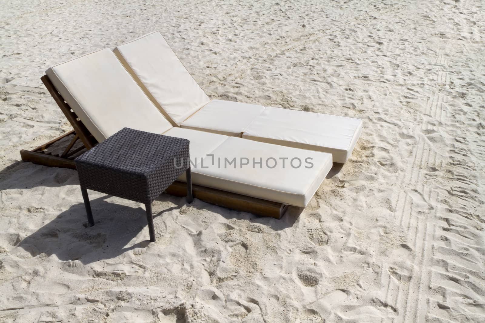 A pair of beach lounge chairs with table