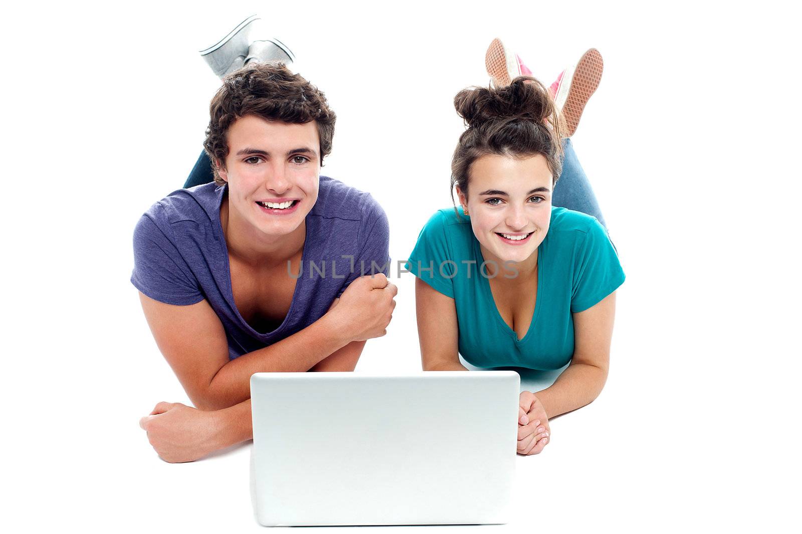 Teen friends enjoying video on laptop together. Studio shot