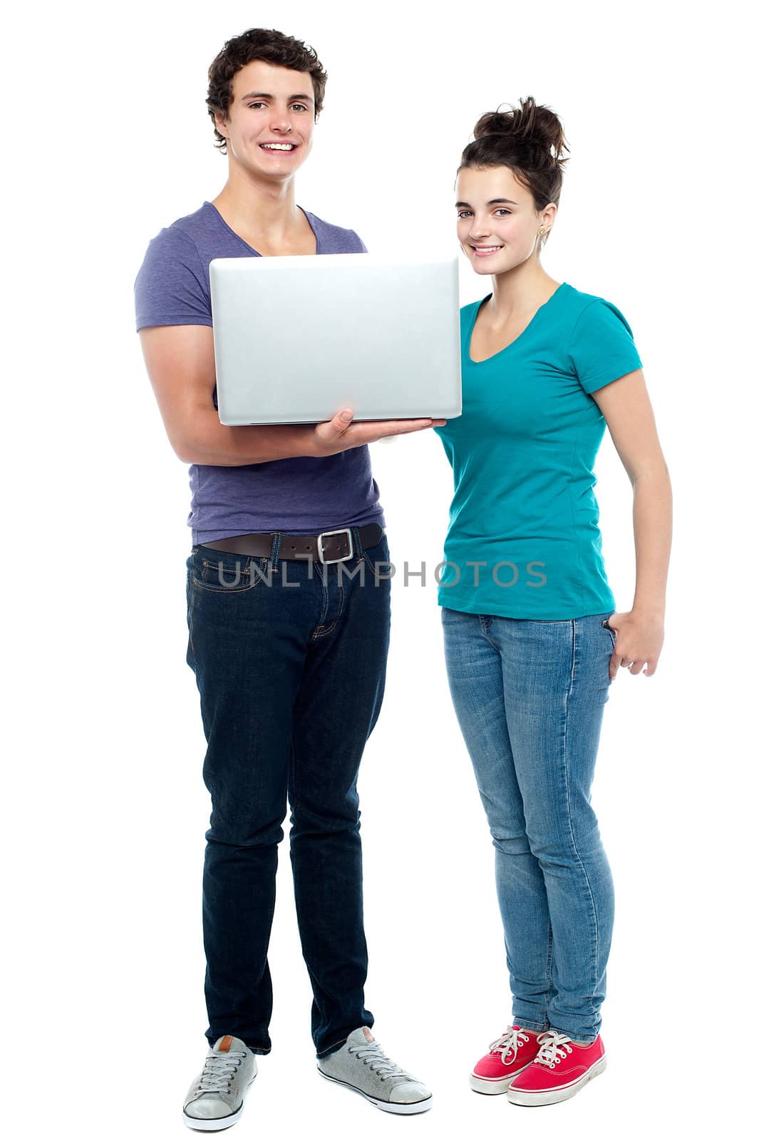 Teen friends holding laptop. Full length shot against white background