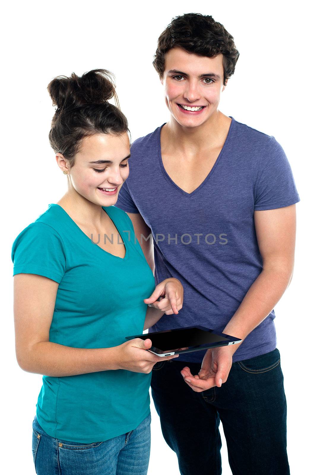 Gorgeous girl with her partner pointing at tablet pc while boyfriend is smilingly looking at camera