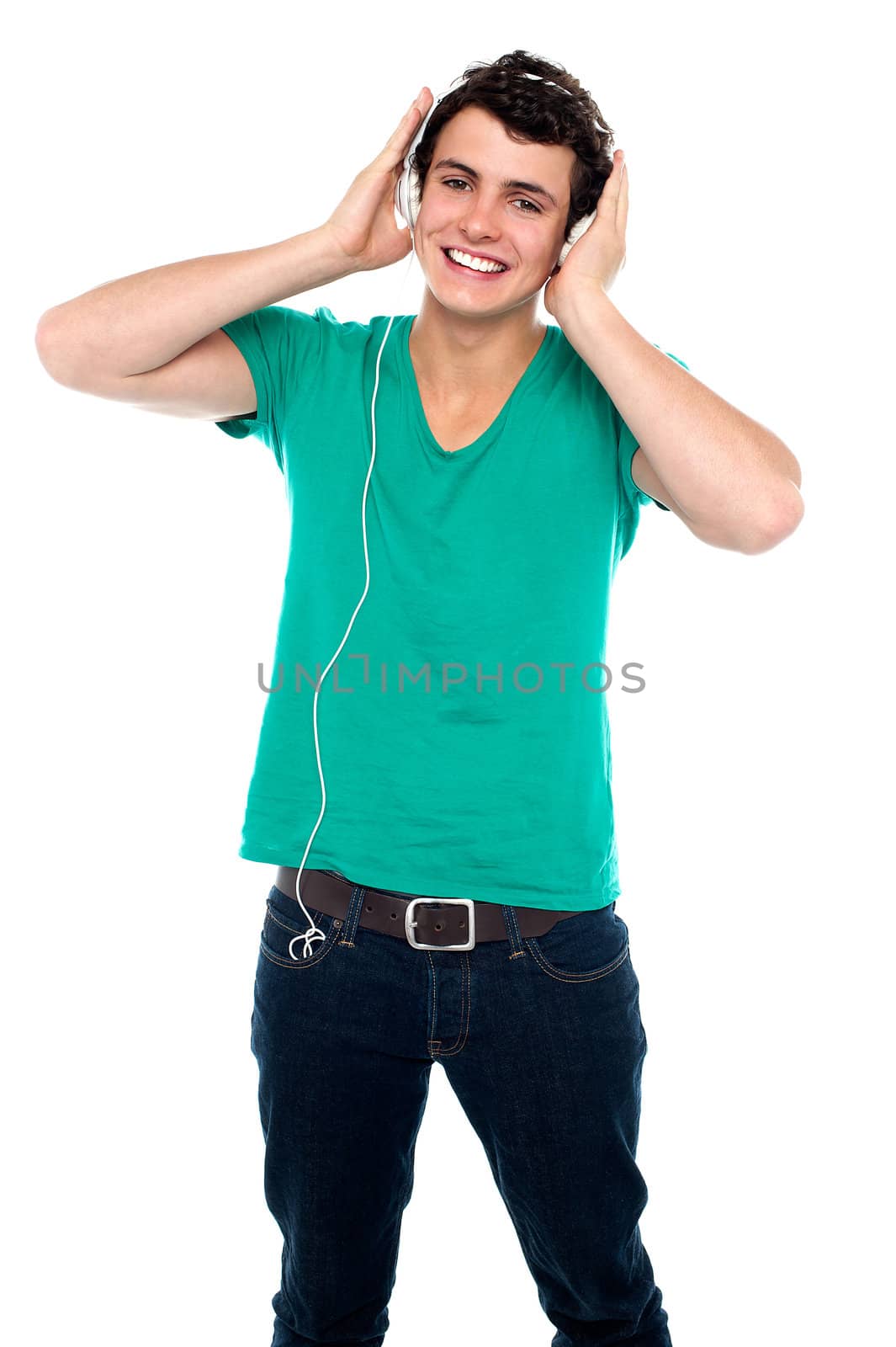 Cheerful guy enjoying loud music holding them tightly to ears