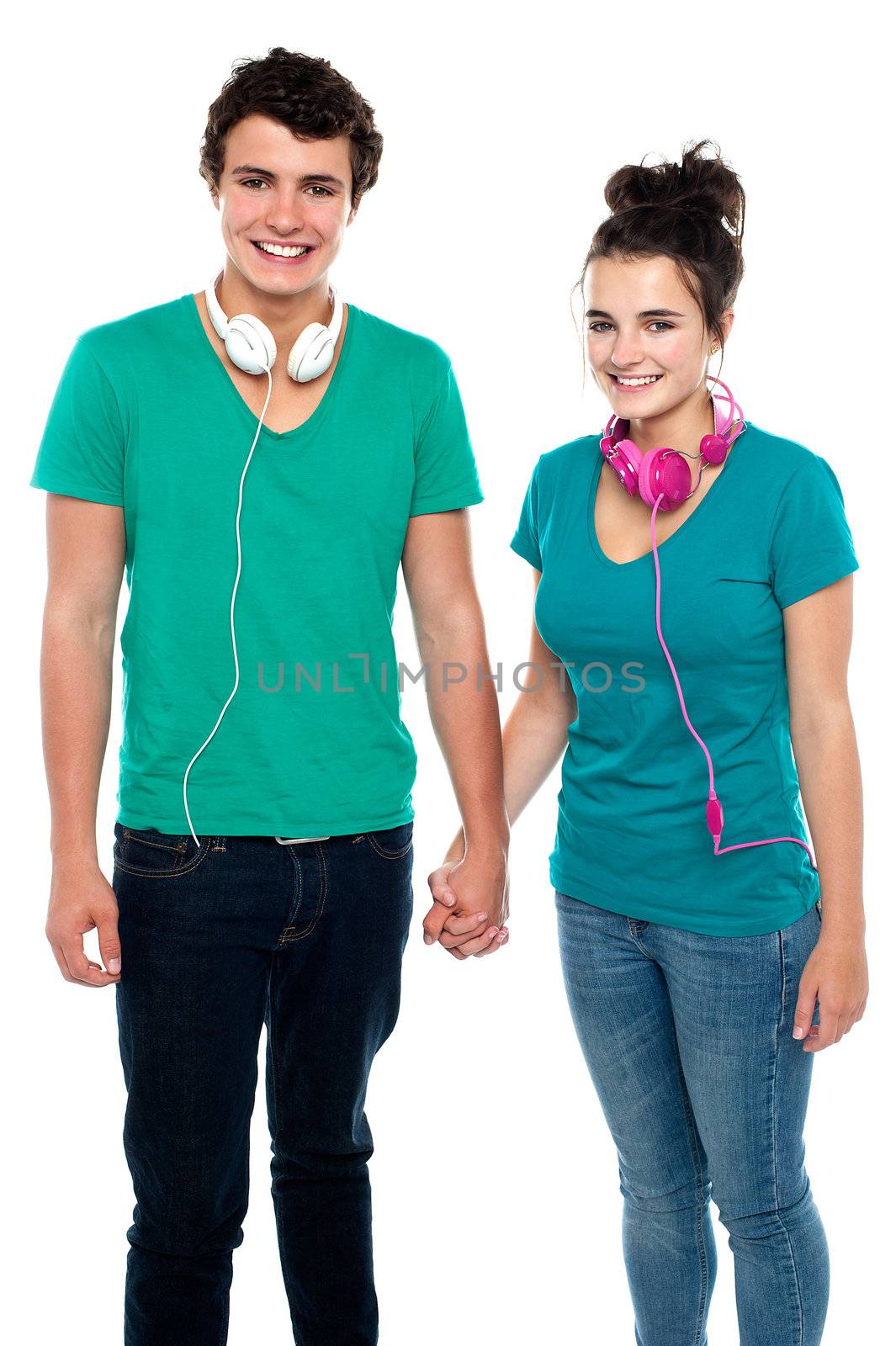 Charming happy young couple with headphones around their necks, holding hands. Great bonding