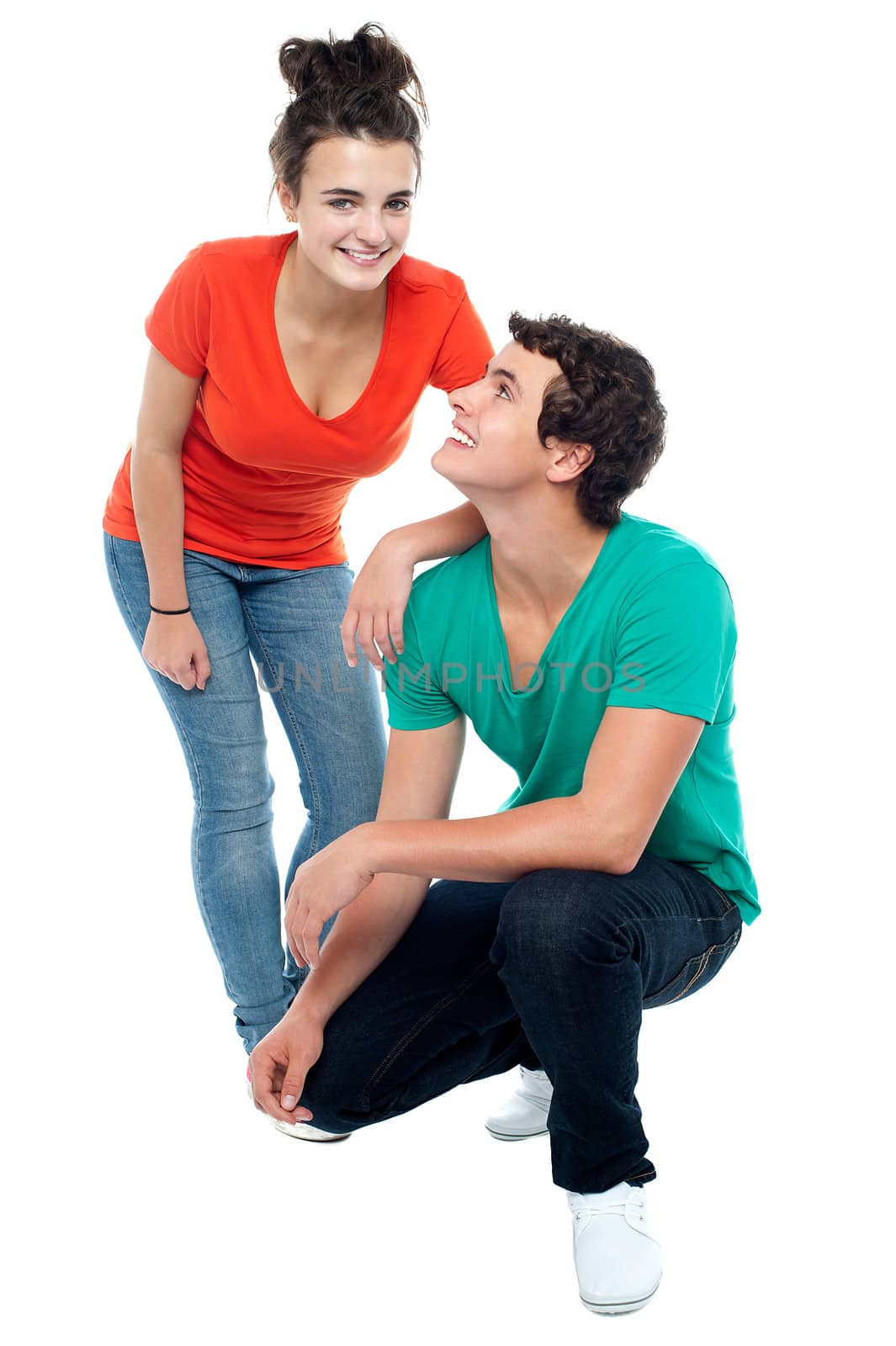 Adorable young guy squatting on floor and looking at his girlfriend