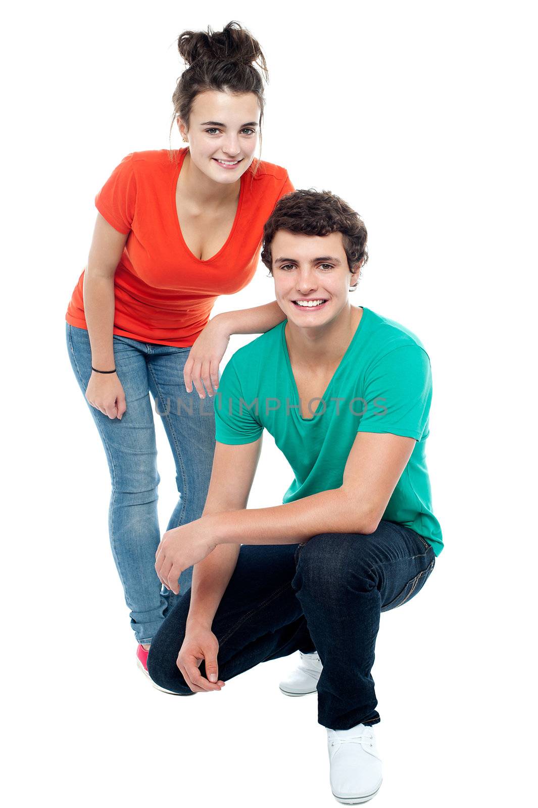 Trendy girl posing with her boyfriend. Guy in squatting posture
