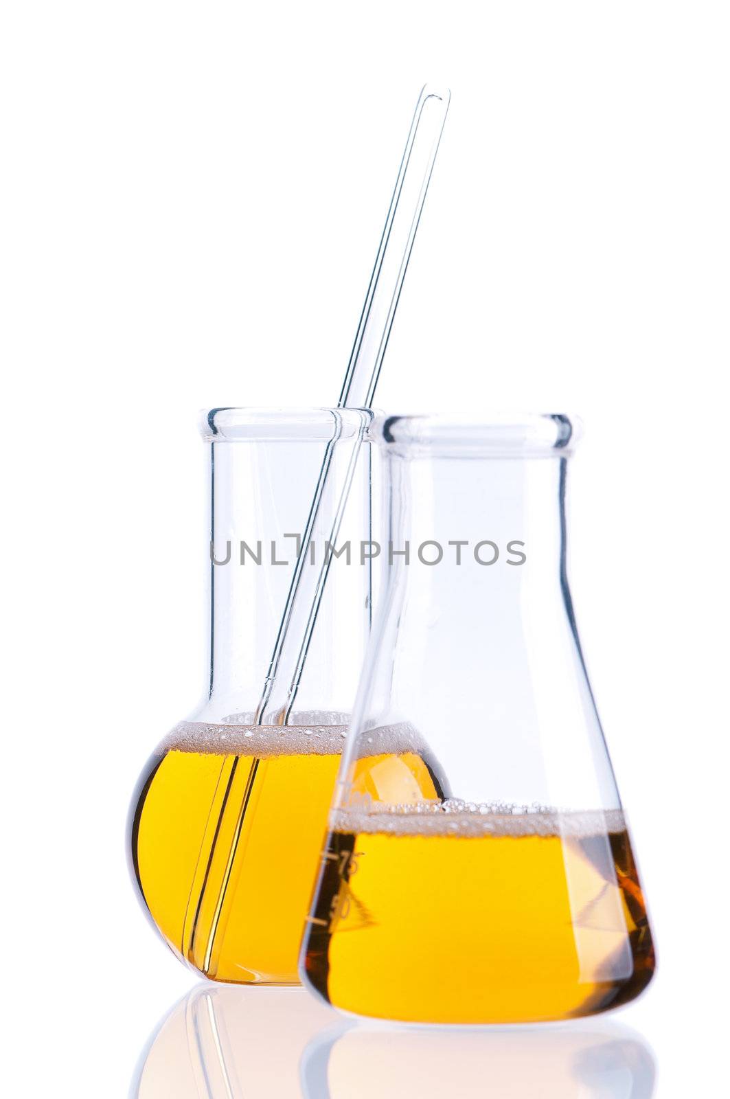 Laboratory glassware with yellow liquids on white background